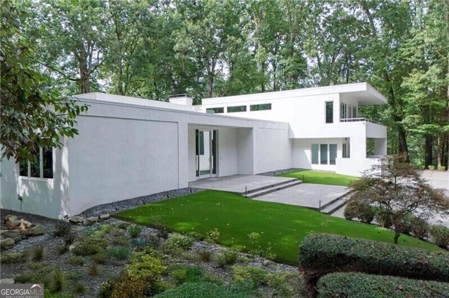 This spectacular contemporary estate on 2.5  private acres stands as a true landmark in Buckhead's prestigious Paces neighborhood. Sophisticated in design yet warm and livable, the property offers a rare balance of modern architecture and everyday comfort. A private drive leads to an expansive motor court, mature landscaping, and a turfed front lawn, setting the stage for the home's striking entrance. Inside, a dramatic foyer with 12-foot ceilings introduces sun-drenched interiors framed by walls of windows, soaring ceilings, and sleek contemporary details. The main-level primary suite boasts a newly renovated bath and an oversized custom closet. Designed for both everyday living and grand entertaining, the main level showcases a vast living room that also functions as a formal dining space for 12+, anchored by a large wet bar ideal for gatherings. Additional highlights include a private office, stylish powder room, and a comfortable family room. The chef's kitchen features stone counters, SieMatic cabinetry, Gaggenau ovens, an 8-burner Russell gas range, and a wine refrigerator, and flows seamlessly into a fireside breakfast room overlooking the lush, private backyard-complete with ample space for a future pool. Upstairs, two bedrooms and two bathrooms are complemented by a spacious bonus room that opens to a covered deck, perfect for year-round outdoor enjoyment. A possible fourth bedroom, currently serving as an office, enhances the home's flexibility. New windows throughout fill the interiors with natural light and frame views of the surrounding greenery. Outdoor living is equally impressive, with porches on both levels, expansive lawns, and multiple areas designed for recreation, relaxation, and entertaining. Located in the sought-after Jackson Elementary district and close to Buckhead's premier dining, shopping, and schools, this remarkable estate offers an unparalleled lifestyle in one of Atlanta's most coveted neighborhoods.