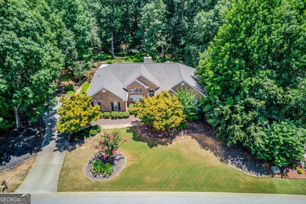 In a word, Serenity. Prepare to be captivated by this exquisitely designed home, where beauty meets rejuvenation and outdoor enjoyment. Located in the beautiful Liberty North Subdivision, this delightful home offers 4 bedrooms, 3 bathrooms, including Master on Main, updated spa like bathrooms, a huge finished basement, and a sparkling in-ground pool perfect for those warm Georgia days. From the moment you step inside, you'll be impressed by the thoughtfully curated details that define every space. Upon entry, you'll experience the wide open spaces this home has to offer. The vaulted ceilings of the gorgeous Living Room and Dining Room create volume and are framed in detail with wainscot trim, crown molding, and marble fireplace. The beautiful luxury vinyl plank flooring flows seamlessly passed the casual dining room and into the chef's kitchen. The kitchen features ample white cabinetry, granite countertops, and a large center island. You're going to love the expansive storage area in the Pantry! The spacious Laundry Room is located just off the Breakfast Area. Down the hall you'll find a luxurious Master Suite showcasing an octagonal tray ceiling with crown molding, and an expansive walk-in closet. The newly renovated Master Bathroom offers a double vanity with marble counter, marble tiled floors, frameless glass shower and a freestanding tub to top it off! Outside the Master Suite, there two additional bedrooms and one newly renovated bathroom boasting a double vanity and gorgeous tile! Enjoy morning coffee on the amazing Screened Porch complete with 6x6 beams and stained bead board ceiling. The grilling deck and steps to the backyard have just been rebuilt. Escape to your own private oasis in the backyard, where a stunning saltwater Gunite pool and expansive stained concrete and paver patio await. Perfect for entertaining or simply unwinding, this outdoor retreat offers a covered sitting area, Stone Fire Pit, lovely landscaping and additional yard space beyond the pool - a blank canvas ready for your own design or use! Additional highlights of this exceptional property are on the Terrace Level where you'll find a lovely bedroom with pool view, a full bathroom with washer and dryer hookups! The Irish Pub style dry bar is complimented with the Chilled Wine Cellar that holds over 480 bottles! There is also a walk up Wet Bar complete with ice maker hookups for a refrigerator. A comfy couch awaits in the Media Room perfect for movie nights. for the exercise enthusiast there is the Fitness Center complete with rubber flooring and a side garage that can invite those nice Spring and Fall days into your workouts! Recent updates include a new roof in 2024, new HVAC in 2019, Pool pump 2023 and filter this summer. Living here is more than just owning a house; it's a lifestyle. Don't miss the opportunity to own this truly special home!