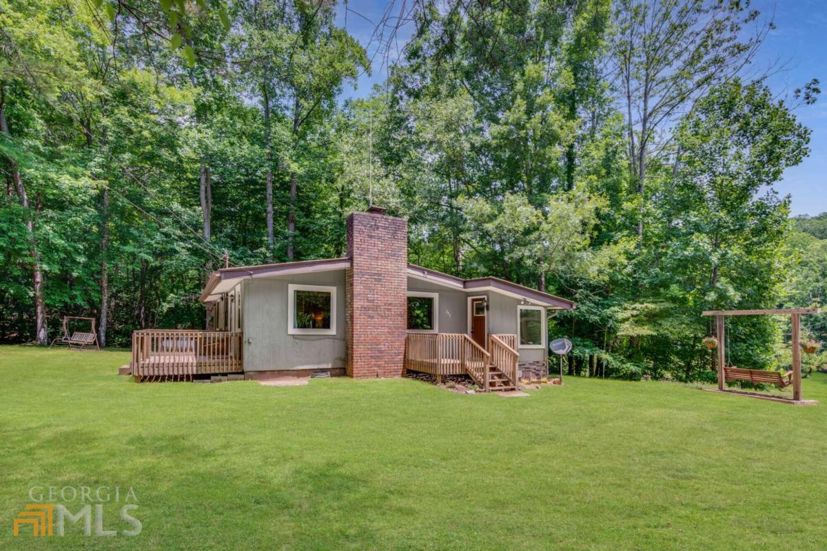 COUNTRY LIVING IN THE HEART OF ELLIJAY ~ UNDER $250,000! This 3BR/1BA Cabin is tucked away in a quiet neighborhood, just minutes from downtown, apple orchards, vineyards, rafting, & the Cartecay River. Situated on 0.81 acres & nestled on a hill overlooking a small Lake, the property offers a level/gentle yard, perfect for your garden & outdoor hobbies, with the North Georgia Mountains as your backdrop! Enjoy privacy in this open floor plan home, with a large living area, kitchen, & dining space for family gatherings. The Living Room features a FIREPLACE and French doors, leading to the deck for additional entertaining & gathering space; ONE LEVEL LIVING! Don't wait; will not last long!