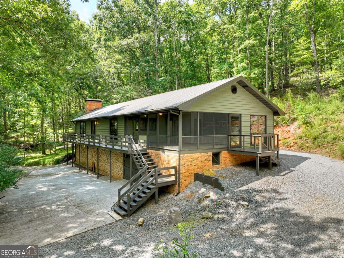 Toccoa River Access. Just 5 miles from Downtown Blue Ridge, this beautifully remodeled 1824 sq ft ranch-style retreat offers the perfect balance of mountain serenity & everyday convenience in the coveted Aska Adventure Area. With Big Toccoa River Access & 225 feet of private stream frontage, you'll enjoy the sounds of nature & the beauty of the outdoors right at your doorstep. Built on a solid Brick Foundation w/ Cedar Lap siding, a Metal Roof (2015), & a circular drive with easy one step or ramp entry, the home radiates timeless quality. A complete remodel in 2011, paired with fresh interior paint, ensures a move-in-ready feel. The great room is anchored by an Arched-Top Brick Masonry Wood-Burning Fireplace w/ full brick chimney (currently fitted with gas logs) & framed by ALL-new windows (Several large Fixed Picture Windows) that flood the space with light. "Wood-look" laminate flooring (2015) adds warmth & durability. Built in Book Shelves add a nice touch to the Cozy Great Rm. The kitchen features Birch cabinetry, New Countertops & Sinks, while both baths have been tastefully upgraded-highlighted by double vessel sinks & New full fiberglass shower units. Custom details abound, from Barn & Pocket doors along w/Polished Pine accent bands, complemented by long transom windows that brighten the bedrooms. Full Size Laundry Rm on the Main Floor. Outdoor living is a true highlight w/a spacious 18' x 22' Screened Porch & newly replaced decking, perfect for relaxing or entertaining. Practical extras include a Pull-Under Garage w/10' ceiling, a dedicated Well Pump room (8'Ceiling), & a detached 8' x 12' Storage Building. Recent updates add peace of mind with a newer washer, dryer, refrigerator, hot water heater, & serviced HVAC system. This is more than a home-it's a quality-built, thoughtfully updated retreat in one of Blue Ridge's most sought-after locations. TDS High Speed Fiber Internet Available. Move In Ready all on ONE Floor Living.