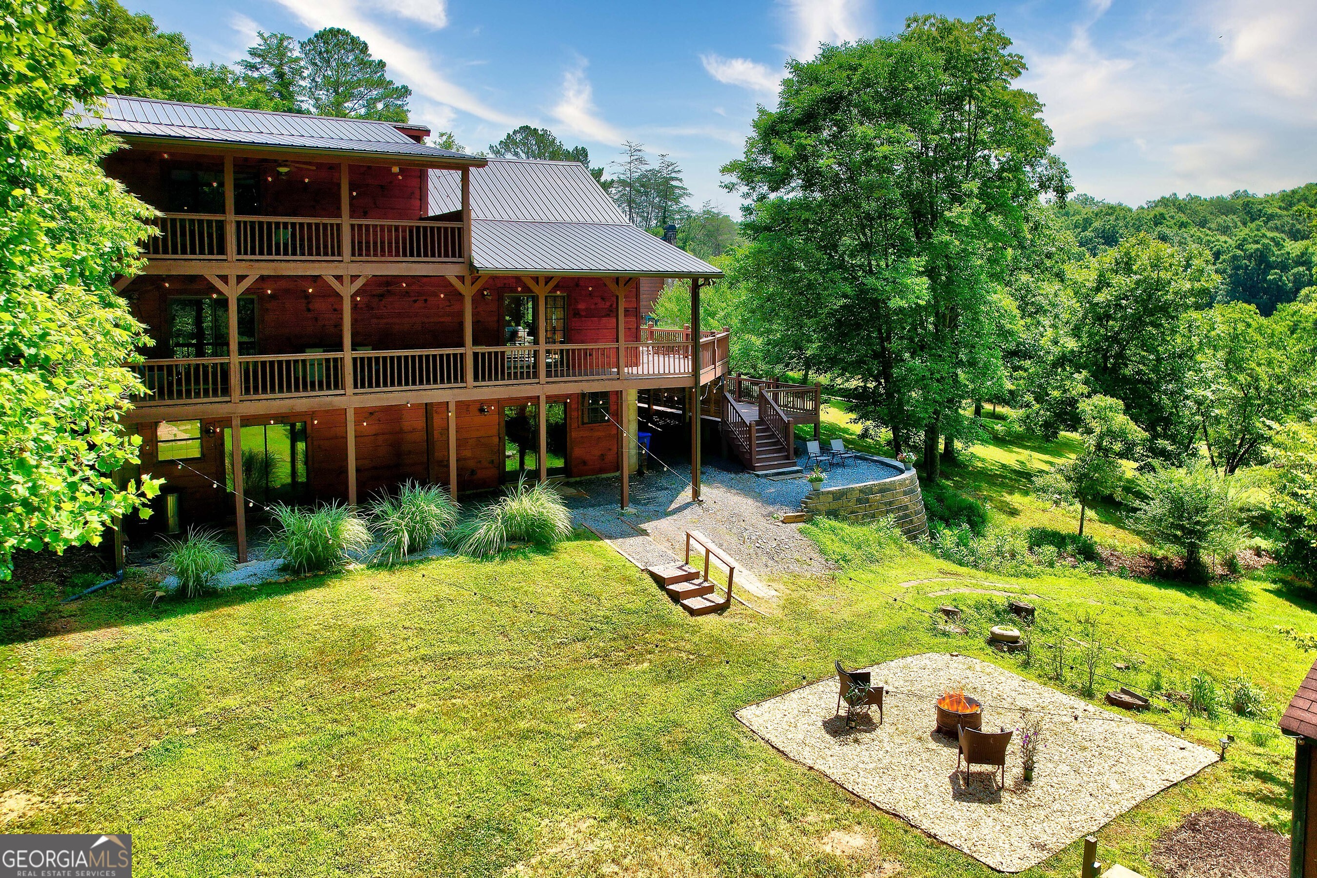 One-of-a-Kind - Your Mountain Lifestyle Awaits! This 4-bedroom, 3.5-bath, three level 2940 sq ft cabin isn't like the rest-buy the home and embrace the Blue Ridge lifestyle! Sitting on 2.2 acres of flat, usable land, this mountain retreat is just 3 minutes from Old Toccoa Farm's premier golf and social club and steps from world-renowned trout fishing at ancient Indian fish traps. Only 3 miles from iconic Mercier Orchards, and 5 miles to town- enjoy convenient access to golf, hiking, fishing, shopping, and more! The main level features a spacious open-plan living/dining area with dramatic floor-to-ceiling picture windows and a cozy gas fireplace-perfect for relaxing after adventure-filled days. The private oversized master suite with a jetted bath, his-and-her vanities and shower features sliding glass doors leading to the covered porch. The spacious open plan kitchen with pantry and dining counter is the ideal setup for entertaining on this level. Wraparound wooden decks (one with a handicapped access ramp) offer private tree views (you own the trees!) from three sides, showcasing bountiful wildlife, and abundant birdlife including hummingbirds and cardinals. The upper level boasts an open loft with a two-person electric sauna featuring infrared lighting-this space is ideal for extra sleeping, an office, or additional private guest retreat. You'll be amazed by this 2nd master bedroom with a private spacious deck, accessed via glass sliding doors, which overlooks the backyard with nature views and wishing well. In addition, this upper level boasts a 2nd br and a bathroom (tub/shower combo). The carpeted terrace level includes a spacious open living/game room with a refrigerator, storage, and an oversized bunk room sleeping 8. Two sets of glass sliding doors lead to a graveled terrace, hot tub/overlook area, and yard access. Additionally, there is a large, insulated toy /entertainment shed with electricity which is ideal for storing outdoor toys. The oversized attached covered carport accommodates multiple cars. Perfect for family gatherings, formal or casual parties, or income potential, This updated home- exterior cedar wood and all decks have been professionally cleaned and re-stained. New retaining wall at carport area. New gravel terrace and garden wall feature and oversized dropdown party deck (built strong for a hot tub) with dedicated electrical. New carpet on terrace level. New window wall and extensive yard renovation with multiple fire pit, garden and seating areas added- is waiting for you!