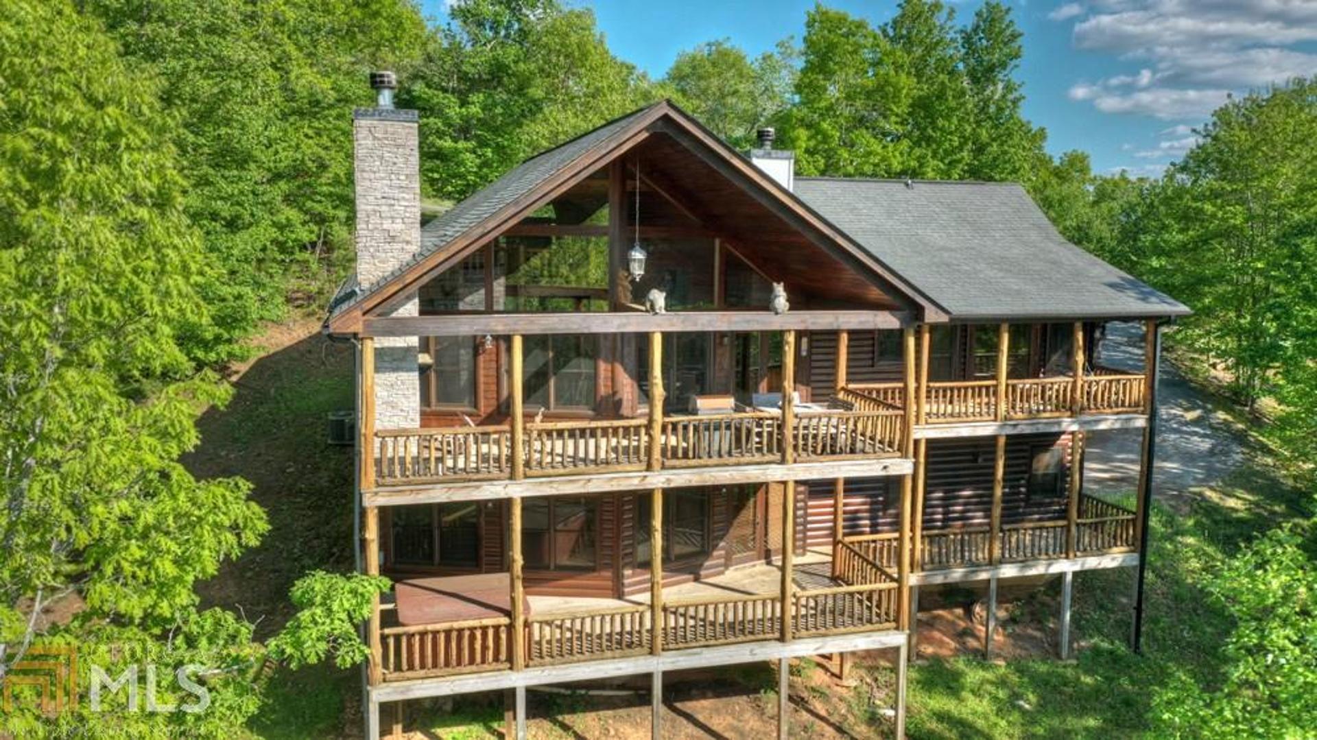 Mountains, mountains, mountains! This immaculately maintained lodge is situated on 2.05 acres in the highly sought after Bear Mountain Ridge subdivision with all paved access and long range mountain views that will take your breath away. The main level features 3 BR/3 BATHS, cathedral ceilings, gorgeous true hardwood floors, floor to ceiling fixed glass and stacked stone fireplace in the living room, stainless-steel appliances, beautiful custom bar, sound system in every room, clawfoot bathtub, walk-in custom tile shower, and an oversized loft area currently set up as an office. Downstairs is truly its own separate living quarters featuring a spacious den, wet bar/kitchenette, 1 BR/BATH, and garage. Enjoy the peacefulness of feeling like you are a world away yet only miles from downtown Blue Ridge and McCaysville. Come enjoy the mountain life...