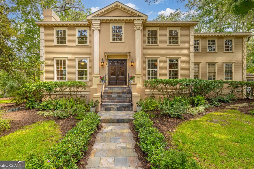 Set in one of St. Simons Island's most desirable neighborhoods, this 4,150 square-foot home blends timeless architecture with extraordinary custom details. From the imported European entry doors into the marble foyer and sweeping, two-story, curved staircase, every element reflects craftsmanship and care. The excellent floor plan features an open-concept kitchen/family room, as well as a lovely living/dining combination with a marble-surround fireplace and handsome study. This combination offers spaces for the entire family to gather and spaces for gracious entertaining and quiet retreat, providing the best of all worlds. A custom, gourmet kitchen is designed for both function and beauty. Outfitted with exceptional custom cabinetry featuring beautiful leaded glass fronts and soft-close drawers fitted with organizers, a mahogany island, Sub-Zero refrigerator and Bosch appliances, a Thermador convection oven and a large walk-in pantry, the space opens to the family room with its raised-beam ceiling which flows into the outdoor space. There are granite counters, a pot filler backed with tile and brick mosaic and instant hot water. The owner's suite is a sanctuary featuring its own marble-surround fireplace, custom closets, a dressing area, and a spa-like bath with marble steam shower equipped with eight shower heads, a Jacuzzi tub, sauna, and water closets that include a bidet. Additional highlights include three additional bedrooms, and ample storage with a floored attic, a storage loft over the garage, and a workshop. The workshop could easily be converted into an artist's studio or a gardener's haven. Outdoors a self-cleaning, heated saltwater pool and terrace form the centerpiece, complemented by a pool house with kitchen, bath and dressing room. A slate floored porch with day bed swing overlooks the pool. The .61 acre lot provides privacy and character with mature landscaping, a stucco walls, and an adjacent pond complete with seawall, gazebo and river rock walkway. With leaded glass accents and carefully curated finishes throughout, this residence is as functional as it is refined.