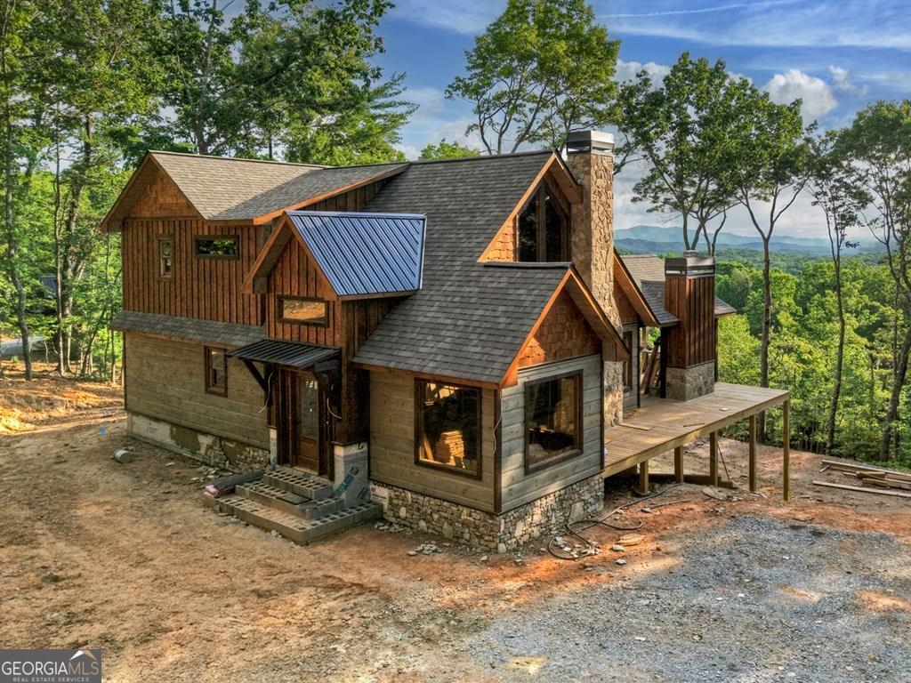 New Construction - Imagine beginning each day surrounded by awe-inspiring mountain views, tranquility, and privacy-this exceptional 3-bd, 3-ba new construction home perfectly captures the essence of North Georgia mountain living! Situated on private, usable land, there's ample space to roam, add a fence for your pets, or create the ultimate outdoor oasis, all while preserving the spectacular mountain vistas and open spaces you desire. Thoughtful rustic finishes and rich wood details throughout provide the inviting charm of a classic mountain cabin. From the striking exterior featuring an appealing blend of wood, stone, and metal, to the open and naturally lit floor plan, every detail was chosen to elevate your mountain lifestyle. Effortlessly enter the main level, where expansive windows frame nature's beauty. Gather around the cozy stone fireplace or create culinary masterpieces in the kitchen, featuring custom cabinetry and granite countertops. Also located on the main level is a generously sized bedroom, full bath, convenient laundry area, separate dining space, and a screened porch complete with an outdoor fireplace-perfect for crisp evenings or serene mornings. The upper-level suite serves as your private sanctuary, featuring a double granite vanity, spacious walk-in closet, shower, and a screened porch ideal for savoring stunning sunrises and sunsets. The versatile terrace level includes an additional bedroom, full bath, wet bar, stone gas fireplace, and plenty of flexible space perfect for a bunk room, family area, games, or office. Step outside onto the expansive concrete porch spanning the length of the home, ideal for entertaining or relaxing in tranquility. Conveniently located near Blue Ridge, Blairsville, and all the top North Georgia attractions-shopping, dining, wineries, hiking, tubing, festivals, and more-this home is ideal for full-time residence, vacation escapes, or lucrative short-term rental opportunities. Ask about our rental projection.