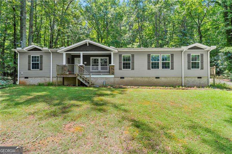 Welcome home to this meticulously well-maintained 3 bedroom, 2 bathroom manufactured home sitting on a permanent foundation! Situated on one level acre of land in the highly desired Sequoyah District, this home has NO HOA and plenty of wooded privacy! Bring your RV or outdoor toys! Inside, you will find an open concept, main living area featuring wooden beams and a gas log fireplace. Just off the family room is your spacious kitchen/dining area featuring a large island and stained kitchen cabinets. Your primary suite is over-sized and offers his/hers separate walk-in closets and vanities! Enjoy soaking in your garden tub while enjoying the nature views! On the other side of the home, you will find two secondary bedrooms with large walk-in closets as well as a secondary bathroom. Quick and easy access to East Cherokee Dr; Hwy 5; Hwy 575 - just minutes to all the shopping and dining of Canton, Woodstock or Hickory Flat! FHA and VA approved! Come tour this home today!