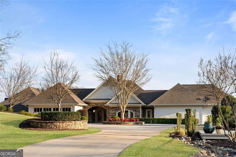 Step into a realm of unparalleled luxury nestled along the pristine shores of Lake Lanier. This meticulously curated estate is more than just a residence; it's a lifestyle sanctuary where elegance and tranquility intertwine, inviting you to embrace the essence of lakeside living at its finest. Prepare to be captivated from the moment you arrive, as the estate's breathtaking setting unfolds before you. Set on 1.15 acres of lush waterfront land, it commands an enviable position, offering uninterrupted panoramic views of Lake Lanier's tranquil expanse. Every inch of this meticulously designed residence has been crafted to celebrate the natural beauty of its surroundings, creating an unparalleled living experience that seamlessly blends luxury with nature. Enter a world where every moment is an opportunity to savor the art of living. From the grand entrance, you're greeted with sweeping vistas that capture the ever-changing beauty of the lake, from the soft hues of dawn to the mesmerizing spectacle of twilight. Each moment becomes a celebration of nature's grandeur, inviting you to immerse yourself fully in the magic of lakeside living. Venture outdoors, and you'll discover an oasis designed to elevate your leisure pursuits to new heights. Challenge friends to a game on the expansive tennis court, freshly lined for pickle ball or tennis enthusiasts. Take a refreshing dip in the heated infinity edge pool, its seamless design merging effortlessly with the vast expanse of Lake Lanier. And when it's time to unwind, retreat to the sun-drenched patio, where lush greenery and the soothing sounds of nature create the perfect backdrop for relaxation. With nearly 330 feet of shoreline, this estate offers an unparalleled sense of privacy and tranquility, allowing you to escape the hustle and bustle of everyday life. Indulge in water sports, soak up the sun's warmth, or simply revel in the serenity of nature's embrace. Discover the island just a stone's throw away, reachable by either the sandbar or a quick swim. The two islands opposite the house form a distinctive barrier, lending an intimate cove ambiance to the expansive water vistas, ideal for leisurely swims and basking in the sun on the two-story dock. Complete with dual jet ski docks and two slips featuring HydroHoist boat lifts, the dock is fully equipped to cater to your aquatic adventures. Inside, luxury awaits at every turn, with two fully equipped kitchens boasting top-of-the-line appliances and ample storage spaces ensuring effortless organization. Earth tones reign supreme throughout, with timber, steel, stone, and leathered granite infusing the space with warmth and character, creating an atmosphere that is both inviting and elegant. More than just a home, this estate is an embodiment of luxury, tranquility, and endless possibilities. Whether you're seeking a serene escape, a venue for unforgettable gatherings, or a place to create cherished memories, this property promises to exceed your every expectation. Embrace the essence of lakeside living and discover the unparalleled lifestyle that awaits at this exquisite estate. Immerse yourself in the grandeur of its surroundings, indulge in its luxurious amenities, and create a lifetime of memories amidst the breathtaking beauty of Lake Lanier. Schedule your private tour today.