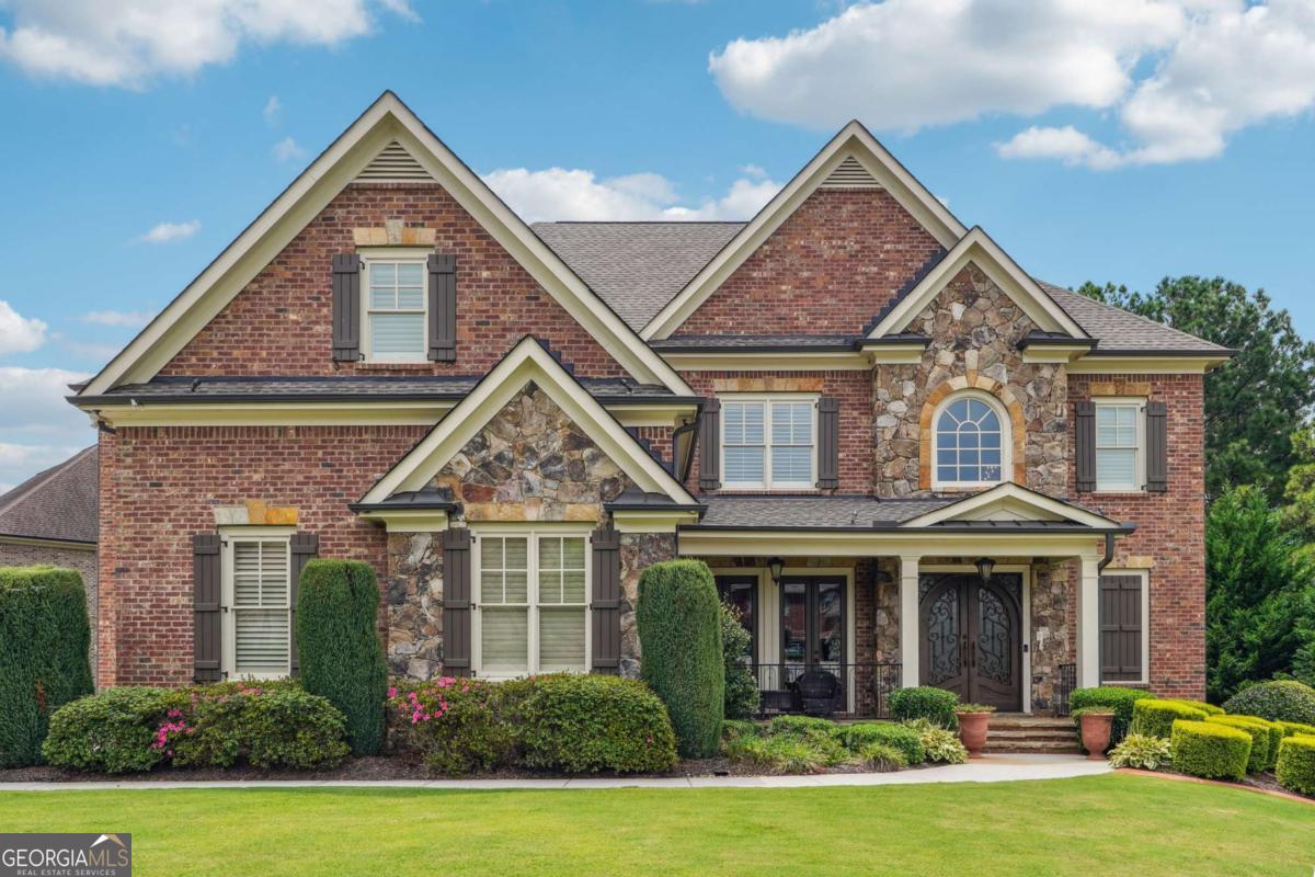 Welcome to Shadow Stone! This beautifully maintained 4-sided brick custom home, perfectly positioned on a corner lot, offers the ideal balance of elegance, comfort, and functionality. This home is sure to impress with all of its beautiful features. A grand two-story foyer sets the stage, opening to a formal dining room and a spacious, open floor plan designed for today's lifestyle. Gleaming hardwood floors flow throughout the main level, while plantation shutters and extensive crown molding highlight the home's timeless details. The family room is a showstopper, featuring custom millwork on the ceilings, custom-built-ins, and a dramatic floor-to-ceiling stone fireplace-an inviting space for both everyday living and entertaining. The chef's kitchen is thoughtfully designed with a large island, granite countertops, stainless steel appliances, a double oven, a gas cooktop, and a walk-in pantry. A bright breakfast room with abundant natural light and an adjacent 3-season room provide the perfect spots to begin your day. A convenient main-level bedroom with a full bath offers flexibility for guests or multigenerational living. Upstairs, the oversized primary suite is a retreat of its own, featuring tray ceilings, a cozy fireplace, a sitting area, a luxurious spa-like bath boasting dual vanities, a jacuzzi tub, and an expansive double-head walk-in shower, with a walk-in closet providing generous storage. Three additional bedrooms with tray ceilings and en-suite baths complete the upper level. Outdoor living is just as impressive, featuring a large covered deck plus a separate open deck ideal for grilling, dining, or simply enjoying the peaceful backyard setting. This executive estate is one you have to see. Its spacious floor plan allows for hosting the best of events.