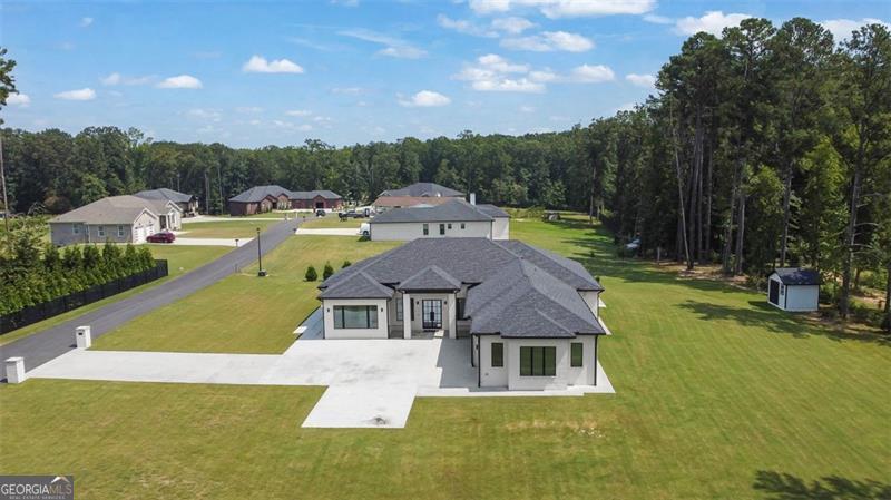 This beautiful ranch home offers comfort, flexibility, and efficiency on a full acre with no HOA. The interior is filled with natural light from oversized windows, paired with deluxe blinds that adjust from open daylight to complete privacy. Real hardwood floors with a durable mono coat finish are installed over insulated subflooring, providing long-term durability and temperature control. The open layout includes a dedicated office/flex space, ideal for remote work or running a small business from home. Inside you'll also find extra closets for added storage, and outside a shed for lawn equipment and essentials. A long driveway leads to a 3-car daylight garage with plenty of space for parking and projects. Built for efficiency with two HVAC systems, four-side brick, and full insulation, this home keeps utilities low with only water and electric (on septic). Unbeatable location: walking distance to Hebron Christian Academy, zoned for excellent schools, and minutes to Hamilton Mill, Mall of Georgia, Topgolf, Andretti, golf, and parks. A rare opportunity for modern ranch living with abundant storage, home-business potential, and a private 1-acre setting with no HOA.