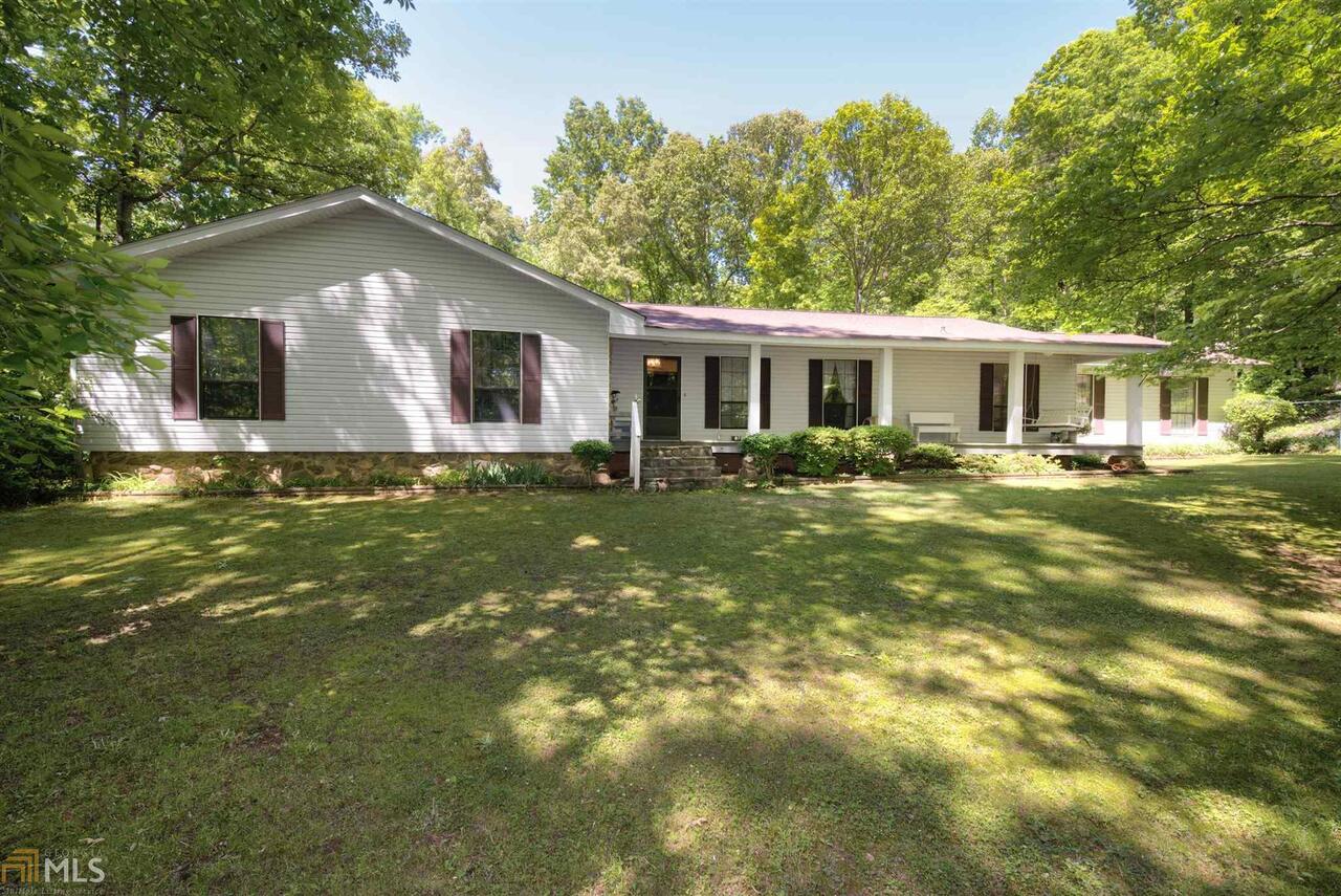 Move to the country--but be just 10-15 minutes from the city, Kroger, interstate and hospital. 20 minutes to Cleveland. No HOA!! Rock on the front porch to hear the sounds of silence except for bird songs. Wood burning stove at huge fireplace and exposed wood beams gives such comfort from work and stress. Large bedrooms upstairs and down, family room, dining room. Two screened porches plus patio on lower level. Lots of storage in basement with shelving--think crafts, online business, etc. Huge storage/workshop room beneath master bedroom. Good space for a garden, too. Cleared area around house then a canopy of forest. Private-private-private! Setup homestead--Grow your own vegetables and raise some chickens. Sellers are sad to move away but this will allow you to enjoy the peaceful setting on three + acres. Take a closer look for a change of pace.