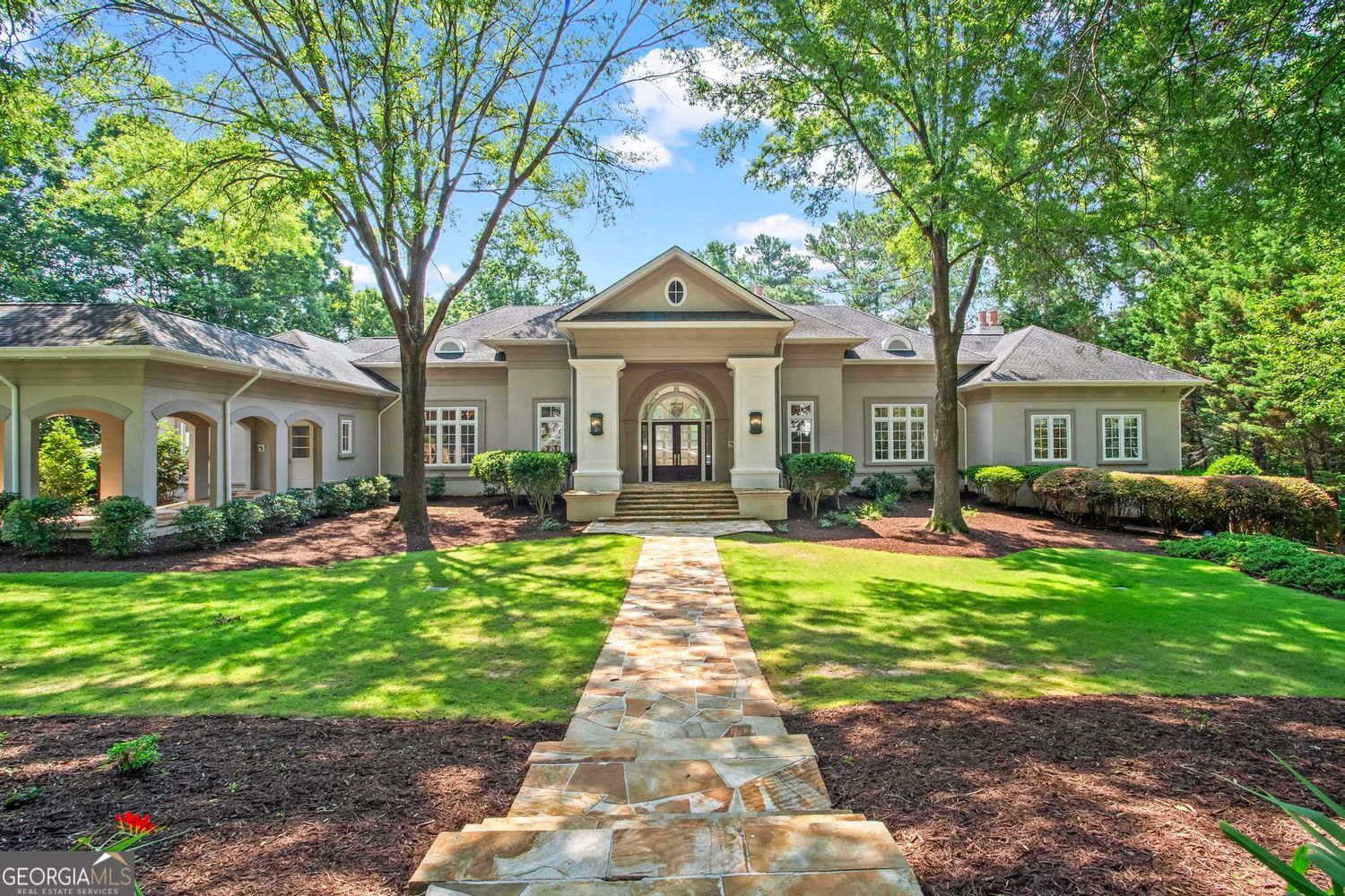 Tucked within the coveted gates of Country Club of the South, this European-inspired estate combines timeless elegance with modern livability. Offering more than 11,000 square feet of luxury living space on 1.72 landscaped acres overlooking the golf course, this home captures the perfect balance of sophistication, comfort, and functionality in one of Johns Creek's most prestigious communities. A stately flagstone walkway leads to the columned entry and soaring foyer, where 30-foot ceilings, a sweeping staircase, and architectural accents create an unforgettable first impression. The grand room showcases two-story windows framing views of the pool, terraces, and manicured grounds, while natural light fills the space with warmth and character. Designed for both everyday living and entertaining, the formal dining room features marble flooring and a Butler's Pantry. The gourmet kitchen is a true chef's haven, complete with custom maple cabinetry, granite countertops, a large center island, and commercial-grade appliances. A bright breakfast room, fireside library, private office, and screened-in porch provide spaces for gathering or quiet retreat. Two en-suite bedrooms complete the main level. The daylight terrace level serves as an extension of the home's lifestyle. Here you'll find a primary suite retreat with a fireplace, spa-like bath, and patio access, plus a second full kitchen, media room, mirrored fitness studio, sauna, laundry, and additional en-suite bedrooms-ideal for multi-generational living or hosting extended guests. Outdoor living is equally impressive. The pool area with flagstone decking is surrounded by mature landscaping, patios, and multiple lounging areas, perfect for alfresco dining or summer entertaining. A breezeway connects the residence to the detached four-car garage, offering abundant storage and parking while enhancing the estate's functionality. This property is more than just a home; it is a lifestyle-one that blends privacy, luxury, and resort-style amenities in a community known for its prestige and security. From the golf course views to the extraordinary indoor and outdoor living spaces, this Johns Creek estate offers a rare opportunity to create lasting memories in one of North Atlanta's most sought-after addresses.