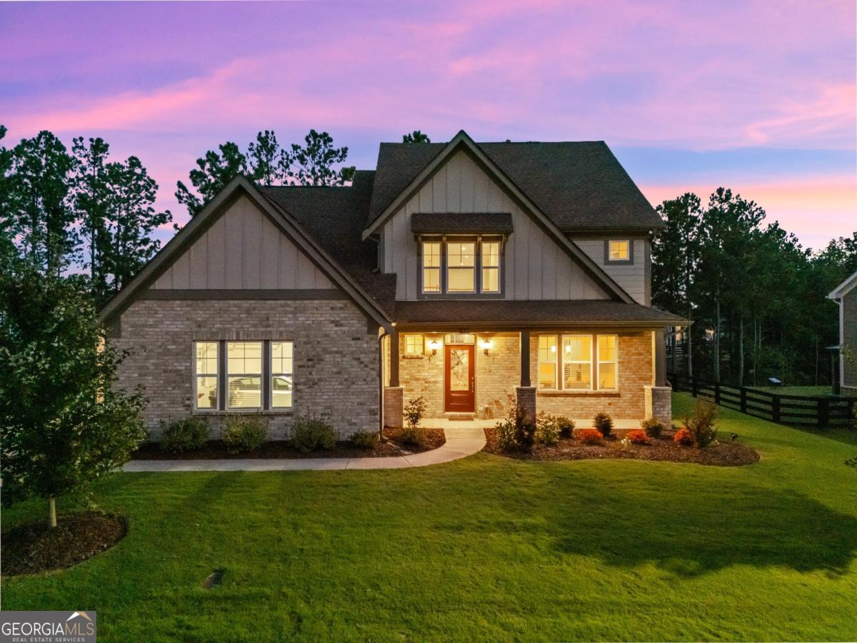 Welcome to this stunning north-facing home, built in 2022 and located in one of Forsyth County's most desirable communities. With classic brick accents, a side-entry 3-car garage with epoxy flooring, and beautiful curb appeal, this property combines modern comfort with timeless style. Inside, the open floor plan is anchored by rich hardwood floors and a dramatic two-story stone fireplace that creates a true focal point. The chef's kitchen features a massive walk-in pantry, butler's pantry, and seamless flow into the oversized dining room-perfect for everyday living and entertaining. The main-level primary suite offers a peaceful retreat, thoughtfully positioned near the laundry room with sink for added convenience. Upstairs, you'll find two additional bedrooms, a full bath, and a versatile loft that works beautifully as a media room, playroom, or office. Step outside to a custom-designed backyard retreat. A flagstone patio with retaining wall, stone steps, and a natural privacy screen of trees create the perfect space for relaxing or entertaining. All of this is set within River Rock, a vibrant neighborhood known for its resort-style amenities, active community atmosphere, and top-rated Forsyth County schools. This home offers the perfect blend of luxury, lifestyle, and location-schedule your private tour today.