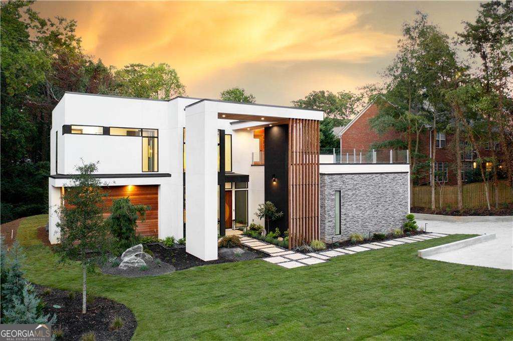 World class MODERN ESTATE in a class of its own, this exclusive estate sits on over an acre in the heart of North Buckhead Complete with a sensational exterior featuring stone, stucco, wood slats, mahogany carved front door, floor-to-ceiling windows, & lush landscaping. A dramatic two-story 20' foyer, 3 Mooi chandeliers, & a floating staircase welcomes you into this stylish estate. The open concept layout features high ceilings, sliding glass doors bringing the outdoors in, & a guest bed/office with a full bath on the main level. The chef's kitchen boasts top of the line Wolf appliances & best of all there is a walk-in pantry/prep area perfect for gourmet chefs. The waterfall quartz countertops & designer light fixtures bring the 14 ft island to life as it opens to the spacious family room w/ a 72" modern gas fireplace with a floor-to-ceiling stone, a built-in wine cellar with the capacity to hold 100+ bottles of your favorite wine, & impressive sliding doors leading you to the incredible backyard. The sophisticated owners suite on the second level has a private covered balcony, attractive gas fireplace, & LARGE custom walk-in closet system. The spa-like bathroom features an incredible rain shower with specially-tailored glass panels, Porcelanosa tiles, a separate Resin soaking tub, & stylish floating double vanity. Two spacious secondary bedrooms with private en-suites, an office, and an extravagant rooftop patio complete the second level. An entertainers paradise awaits in the finished daylight terrace level, features include; custom bar with seating, 2nd wine cellar, two bedrooms, a home theatre, & a large walk-out rooftop patio perfect for entertaining.