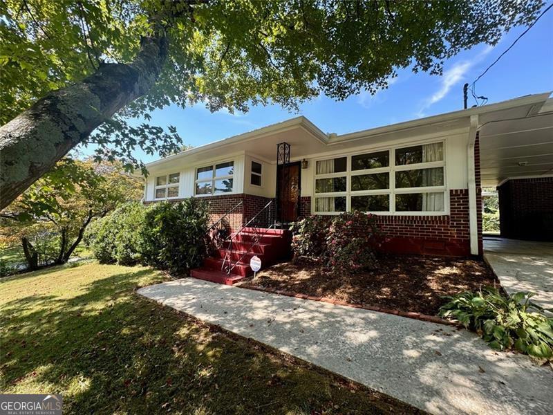 Have you been looking for a move in ready 3/2 north of Atlanta and inside the Perimeter? You may have just found it! This well maintained all brick 1950s ranch sits on a large corner lot with established, manicured landscaping. The positioning of your next home makes you feel as if you are inside a treehouse when you sit in the living room and overlook your yard with large oak trees that provide privacy and shade. Natural light fills the home. The home has maintained the vintage charm with original hardwoods, original tiles, heart of pine paneling and whole house fan. An addition to this home added a large family room with wood burning fireplace and deck.Your primary bedroom features an ensuite bath. The laundry room is located just off of the kitchen in the carport. An outbuilding provides additional storage and the backyard is fenced in. Your next home is nestled in a quiet, established Doraville neighborhood with easy access to 85, 285, Buford Hwy and shopping. Easy walking distance to Brook Park with tennis courts and playground; also easy walking distance to public transportation. Your next home just awaits your special touches. Schedule your easy viewing appointment today!