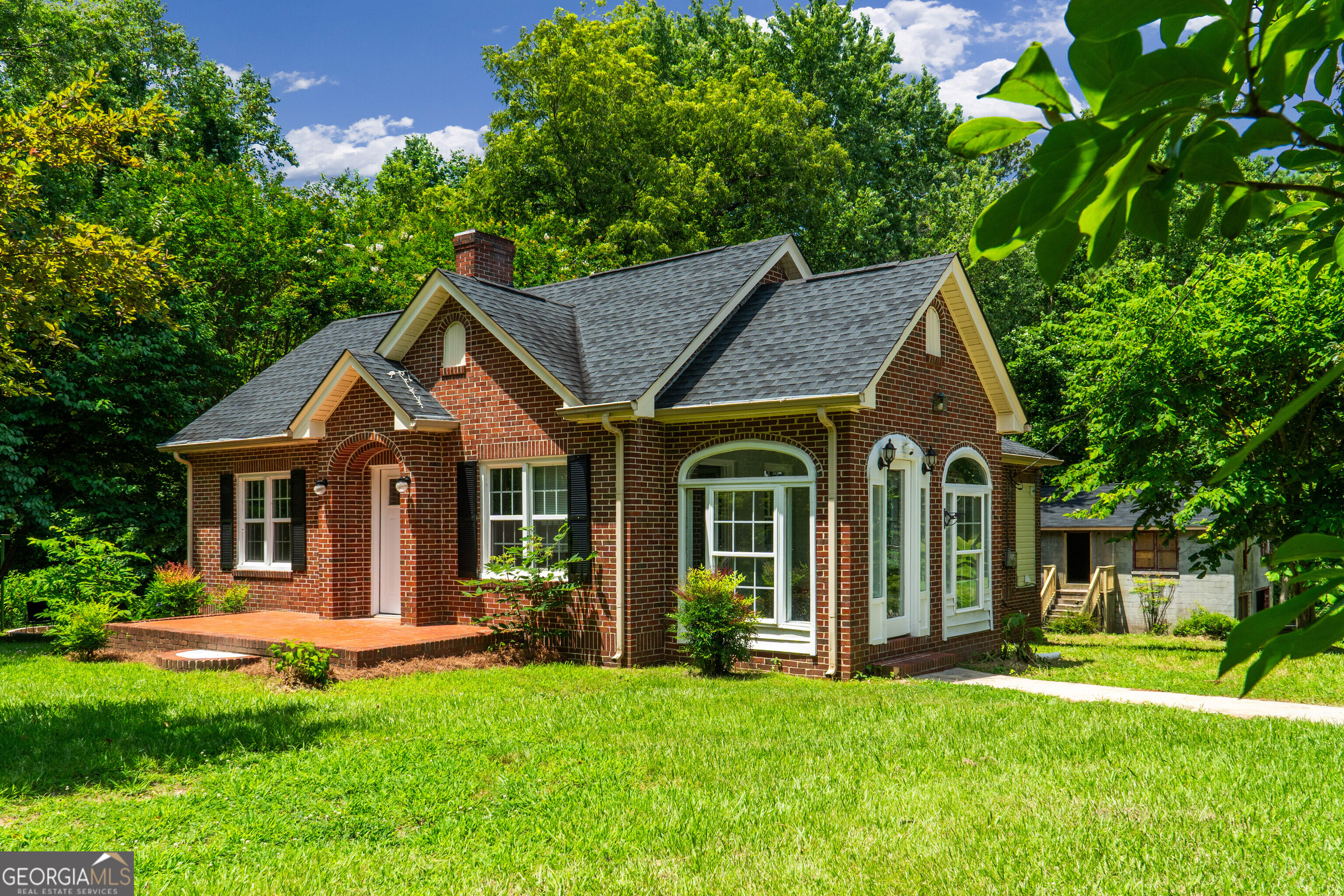 Incredible multi-generational opportunity on just over an acre, this move-in-ready, all-brick beauty on just over an acre is your dream come true. Not only does it offer a charming 3-bedroom, 1-bath brick home - but it also comes with a second fully-renovated 3-bedroom, 2-bath manufactured home, a detached two-car garage with bonus room potential, and a private, peaceful setting ready to host your best life. Let's start with the main brick home: Classic and timeless, with a wide, tiled rocking-chair front porch that makes a memorable first impression. Enter through the finished tiled side porch into a bright living room adorned with a floor-to-ceiling brick fireplace, natural gas heater, brand new LVP floors, a wood mantle, and fresh lighting with a ceiling fan. From there, flow into a large dining room that connects to both the kitchen and hallway. The kitchen is full of vintage charm with original wood cabinets, a custom marble countertop, original oversized ceramic sink, tile floors, and included appliances - all leading into a convenient mudroom/laundry area with a stackable washer/dryer (which stays!) and access to the attached one-car garage/basement offering tons of extra storage. The bathroom is straight ahead down the hall, with beautiful custom tile and a tub/shower combo. The primary bedroom overlooks the front yard and includes a multi-shelved closet. The second bedroom boasts a walk-in closet and wood accent wall, while the third bedroom or flex space (also with a wood accent wall) connects to the mudroom and has its own closet. This home has been thoughtfully updated while still preserving its character. Behind the house, a massive concrete-block detached garage stands ready to serve as a storm shelter, workshop, or future bonus suite - with unfinished space upstairs that could be transformed into a guest loft, office, or studio. To the left of the main home sits the second residence - a modern, stylish 3-bedroom, 2-bath manufactured home with a metal roof, covered carport, and charming wood-front porch with a ceiling fan. Inside, you'll find an open-concept living room with vaulted ceilings, A/C unit, ceiling fan, and gleaming hardwood floors. The kitchen features a custom breakfast bar, laminate countertops, LVP flooring, stainless steel double sink, and included appliances. Step out from the laundry room onto a huge private back deck overlooking the peaceful lot. The primary suite includes its own A/C unit, walk-in closet, and a gorgeous custom-tiled bathroom with high dual vanities and tub/shower combo. Bedrooms 2 and 3 are spacious and share a beautifully updated hall bath with a marble vanity top and tub/shower combo. Between the homes is a custom fire pit, ready for cozy evenings under the stars. Whether you're looking to accommodate extended family, generate rental income, or create your own private compound - this property offers flexibility, privacy, and turn-key comfort, all nestled on 1.03 serene acres. Opportunities like this are rare - schedule your showing today and come fall in love.