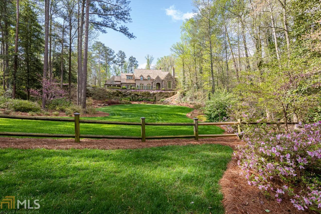 "Quarry Crest," a one-of-a-kind, iconic, gated estate home, sited on a 2.5-acre private hilltop. Built in 2005 by renowned Atlanta builder Bob Goodsell, every detail exudes quality. With updated finishes and appliances added in 2020, this enchanting home is move-in ready.Soaring 12-14 foot ceilings throughout the first floor allow natural light to fill each room of this masterfully designed home. A barrel-vaulted ceiling connects the banquet-sized dining room to the gourmet cook's kitchen and two-story family room where a fireplace prefaces the stunning views of the walkout level yard, heated saltwater pool, tranquil waterfall and inviting loggia. French doors easily open to the breezeway for the full-size server's bar. The main level also features a formal living room as well as a spacious private guest suite and a handsome wood-paneled study - all overlooking the expansive front lawn.A grand staircase ascends to the second level, which hosts the tranquil primary suite. Truly a relaxing haven, this retreat impresses with a bathroom offering separate vanities, huge closets and a morning bar. Three additional, spacious, second-level bedroom suites are served by a large and convenient second laundry room.A playground for all, the terrace level boasts a theater, a 1,000-bottle wine cellar, a professional-size gym with a dry sauna and a guest room or massage room - all served by a full bathroom. The fabulous entertaining areas continue outside to the pool cabana's outdoor fireplace, integrated TV and adjacent grilling area. A Jacuzzi spa overlooks the peaceful waterfall.Additional amenities include a second staircase, a first-level laundry room , a cedar shake roof, a three-car garage and an abundance of room for guest parking.