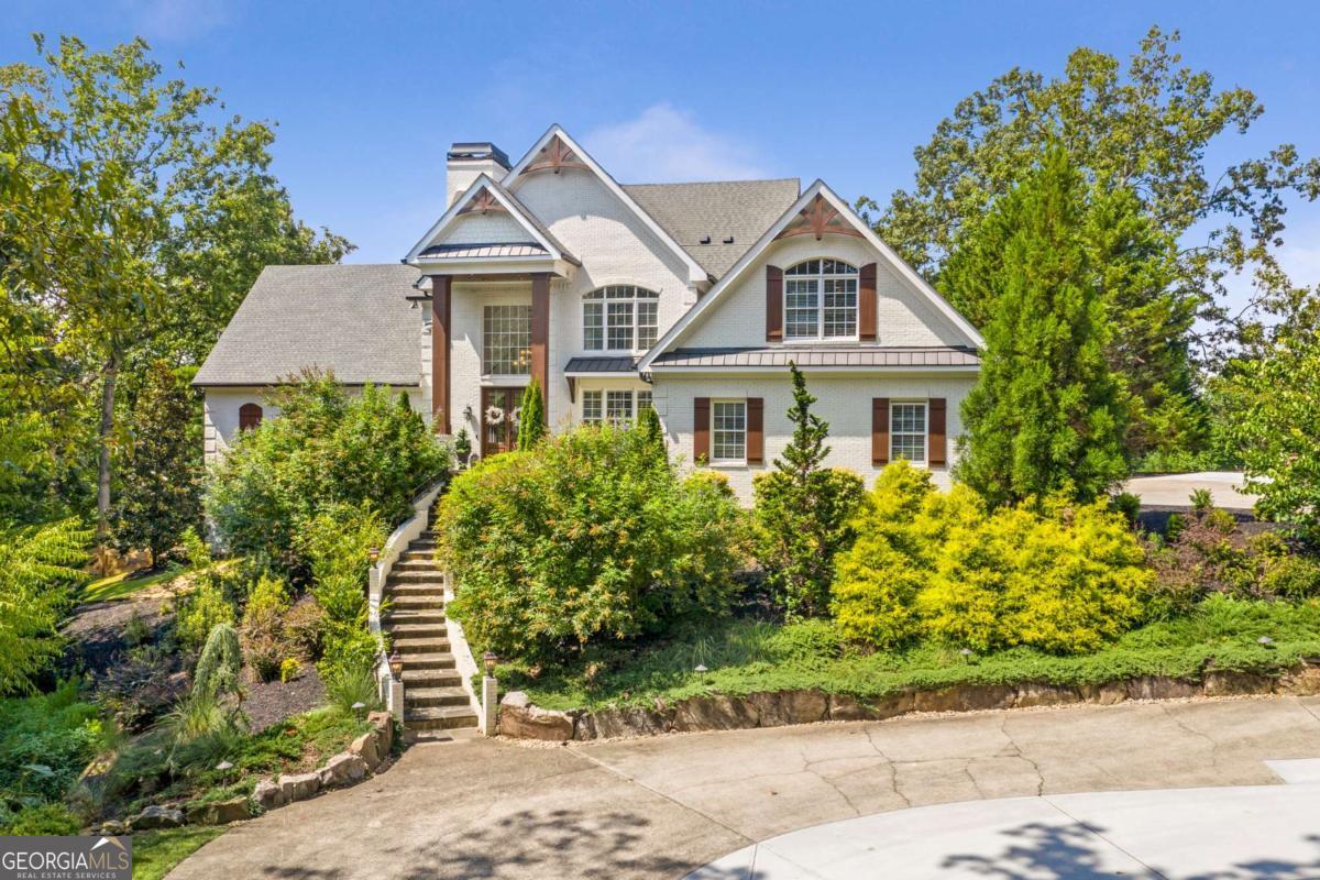 Nestled on the shores of Lake Lanier, this exquisite gated lake house, with 2 story dock in deep water cove, combines timeless elegance with modern luxury, offering resort-style living both indoors and out. Step into the impressive two-story foyer and discover an elegant sitting room/formal dining area, a spacious family room with a cozy fireplace, and a gourmet kitchen featuring Sub-Zero and Wolf appliances, 2 dishwashers, built in ice maker, an oversized quartz island, and dining area filled with natural light. The main level also includes a convenient laundry/mudroom and den with fireplace. The primary suite on the main level offers a private retreat, while the upper level boasts four generously sized bedrooms and two full baths. The finished terrace level is designed for entertaining, complete with a home theater, billiards room, bar, additional bedroom, home office, a full bath and exterior accessed pool 1/2 bath. Guests will enjoy their own private detached guest house, which includes a full kitchen, living space, two bedrooms, and two full baths. A separate three-car garage with storage adds extra convenience. Outdoor living shines with a sparkling pool, Trex deck, outdoor bar and grilling station, and a double- slip dock. This home has been meticulously maintained and enhanced with extensive upgrades throughout. The kitchen has been refreshed with professionally painted cabinetry, while lighting, trim, accent walls, and custom built-ins add a polished touch to multiple spaces. 2 of the 5 fireplaces have been updated, the main fireplace boosting an updated lime wash finish and the upstairs fireplace remodeled for a modern look. The primary suite includes a custom-designed closet with built-in drawers, and the home theater and office have been freshly painted to create warm, inviting spaces. Functionality has been elevated as well, with the addition of EV charging stations in both garages, a guest house laundry hook-up, and a coated garage floor for durability. The guest house also features a brand-new AC system for added comfort. Outdoor improvements include professional landscaping, planter boxes, a brick mailbox, trash can storage, tree removals, the installation of a secure dog run and expansion of drive way space for additional parking. Energy efficiency and smart technology complete the package, with spray foam insulation, a tankless water heater, a variable-speed Trane HVAC system, and full smart-home integration featuring whole-home audio, video, security cameras, and Wi-Fi coverage throughout. This estate represents a rare opportunity to enjoy refined luxury, modern convenience, and effortless lakefront living in a truly turnkey property.