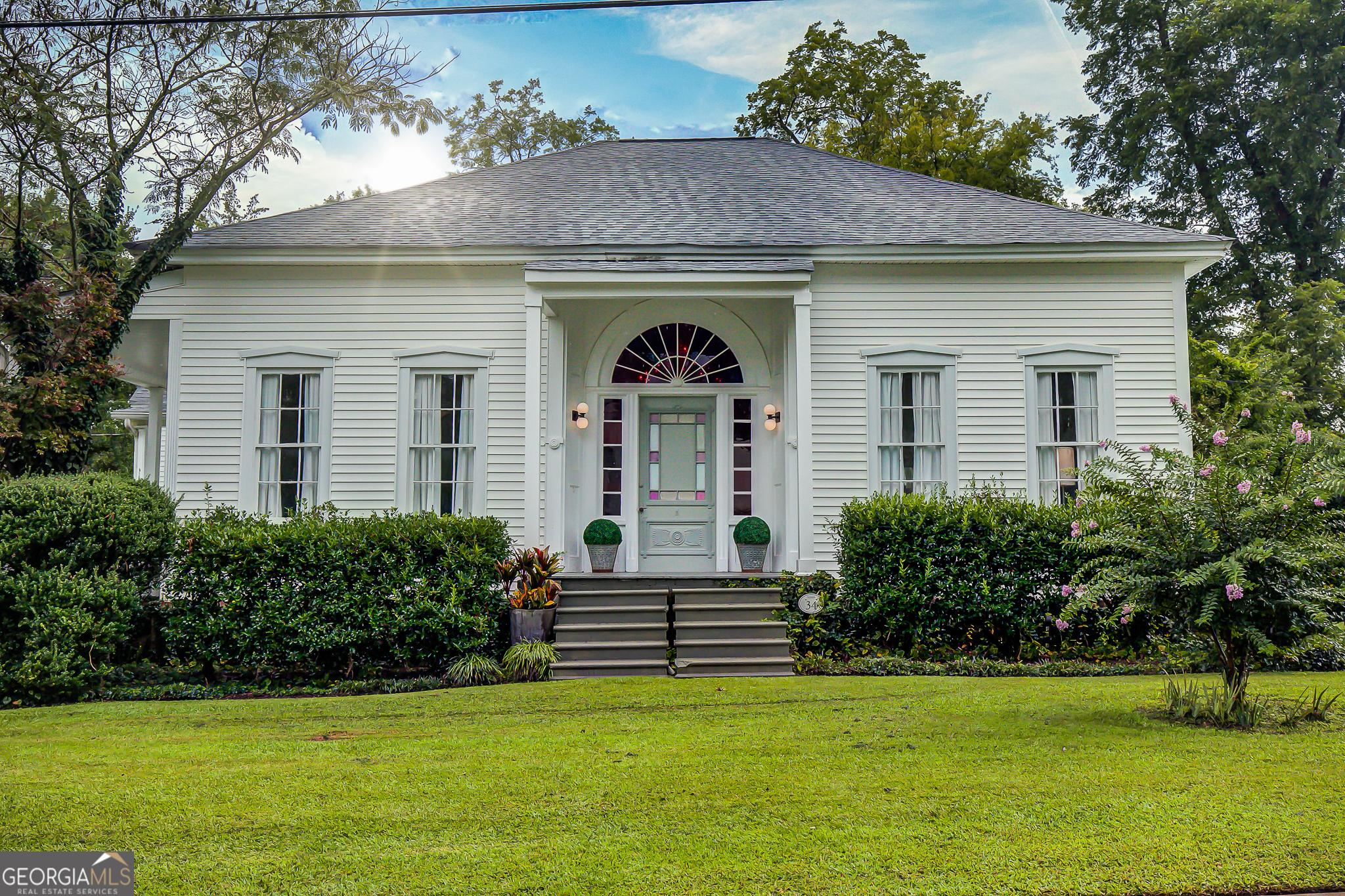 A rare opportunity to own a piece of history in one of Georgia's most beloved small towns. Originally, the Barnes Home, this Historic Circa 1860 home is one block away from restaurants, boutiques, and the many community events that Senoia has to offer. The inviting wide entry hall featuring a 14' ceiling and original red stained glass windows that fill the space with rich warm light. The other rooms are graced with tall elegant windows allowing the natural light to illuminate the gorgeous hardwood floors. A beautifully updated kitchen features custom cabinetry, granite countertops, and a sleek glass cooktop. All blending seamlessly into the homes' historic character. The recently remodeled bathrooms retain a historic feel with a contemporary flare. Perfect for entertaining, the expansive formal dining room, filled with natural light, easily seats 10+, making it ideal for entertaining. Relax outdoors on the veranda or screened-in porch or unwind on the patio by the fire pit surrounded by an iris garden. The property also includes a carport and a detached garage that can double as a workshop or office. This home is truly one of a kind. Historic charm. Premier location.