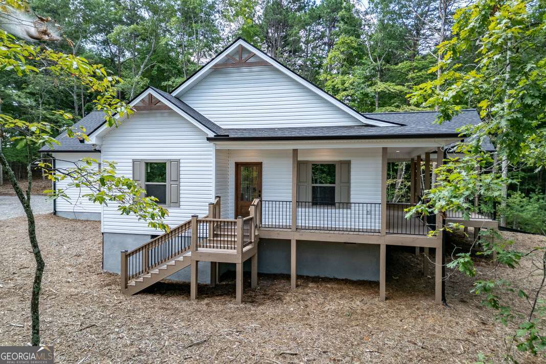 This brand new 2025-built ranch-style home in Blairsville, Georgia offers 1,750 square feet of thoughtfully designed living space on a gentle, one-acre lot with seasonal mountain views and a wooded backdrop. With three bedrooms and two full bathrooms, the home features an open-concept layout that includes a spacious great room with vaulted ceilings and a gas fireplace, an eat-in kitchen with granite countertops, pot filler, pantry, and a grilling deck just off the dining area. Luxury vinyl flooring runs throughout the main living areas, and the cathedral ceilings in the entrance foyer create a warm and welcoming entry. The owner's suite includes a double vanity, tiled shower, and large walk-in closet ready for custom shelving, while the two additional bedrooms also offer walk-in closets-one with direct access to the shared bathroom. Designed for comfort and practicality, the home includes a laundry room on the main floor with a conveniently located water main shut-off, insulated interior garage walls, engineered trusses, a 240-volt EV charger in the two-car garage, vinyl siding and windows for low-maintenance living, and a crawl space foundation. Outdoor living is a highlight with a front wrap-around porch and a back porch featuring a second gas fireplace, perfect for enjoying the peaceful natural surroundings. Located just off Murphy Highway, the property offers easy access to both downtown Blairsville and nearby Murphy, making it an ideal blend of convenience, modern comfort, and mountain charm.