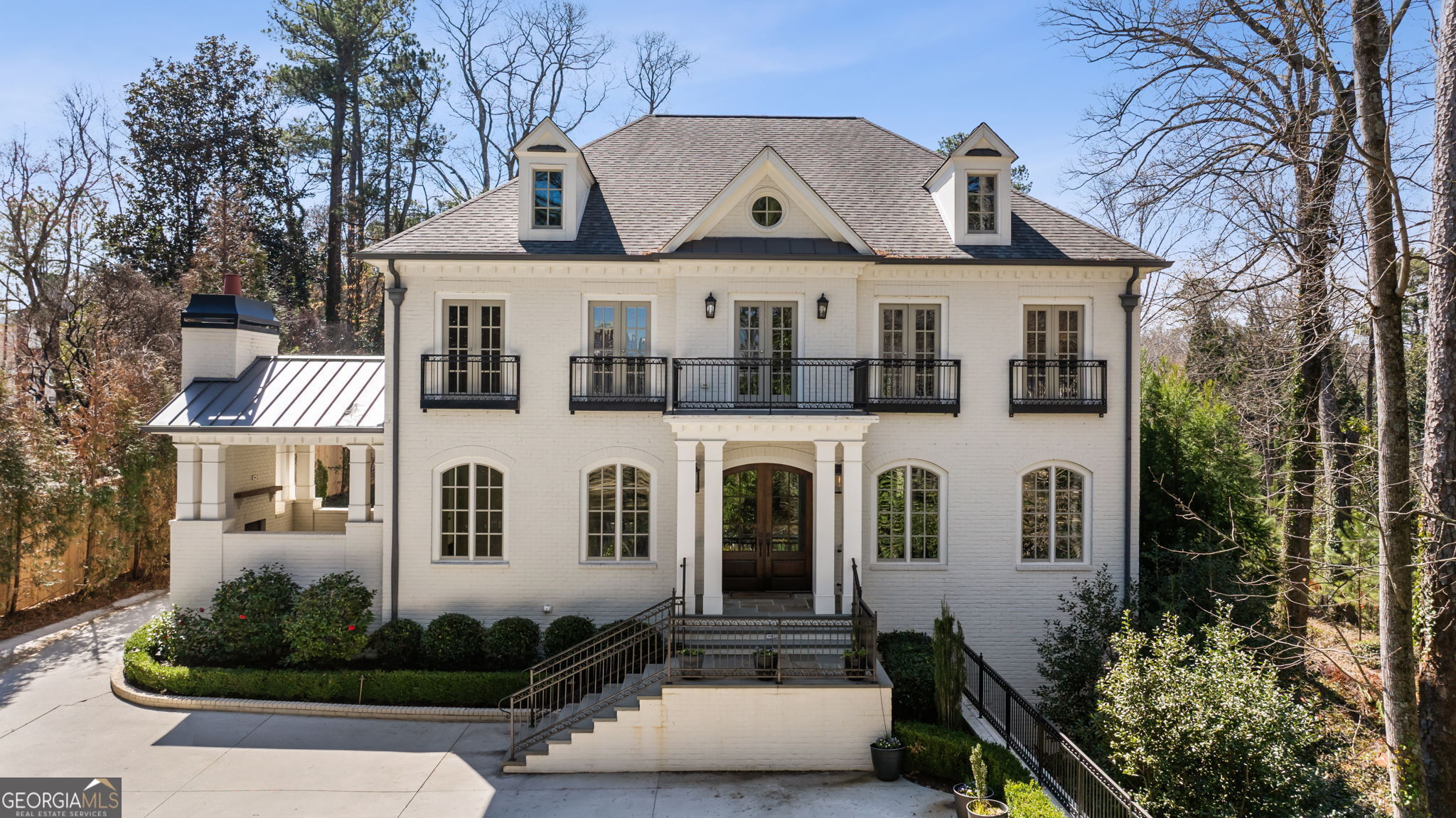 Nestled in the heart of the prestigious Tuxedo Park, this extraordinary residence offers an unparalleled living experience on one of Atlanta's most coveted streets. The open-concept main level is a masterclass in elegance, featuring a gourmet kitchen with abundant soft-close cabinetry and drawers, complemented by beautifully stained beams throughout the family room and breakfast area. Large windows allow natural light to fill the space, creating a bright inviting atmosphere. The main floor also boasts two elegantly positioned staircases, enhancing both the flow and architectural beauty of the home. This level includes a second primary suite, as well as an additional bedroom with its own veranda and fireplace. A separate dog washing room reflects the attention to detail that permeates this residence. Rich hardwood floors extend across all three levels, establishing a cohesive and luxurious aesthetic. Upstairs, five spacious bedrooms, each with en-suite baths and walk-in closets, ensure privacy and comfort for family and guests. A vaulted loft, complete with a walk-out balcony overlooking the front yard, offers a peaceful retreat. The primary suite is a serene sanctuary, featuring a separate sitting area with its own private veranda. The spa-like bathroom offers indulgent finishes, including an oversized tub and shower and an expansive custom-designed closet. The lower level is a true entertainer's dream, featuring a golf simulator, wet bar, card room, pool table, and a fully equipped gym. Outside, the property is adorned with lush landscaping, a full-sized basketball court, and a four-car garage with a workshop and exquisite wood doors. The home is thoughtfully designed for the highest level of privacy, secured with a gated entrance that offers both seclusion and peace of mind. Fully equipped with advanced Control 4 systems, it integrates audio, video, lighting, and security to add a modern touch of convenience. This residence combines refined elegance, innovative technology, and architectural brilliance, offering a lifestyle that transcends the ordinary and redefines luxury.