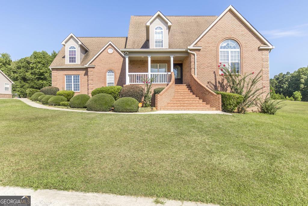 Imagine coming home to this remarkable property, nestled on a generous 1.32-acre corner lot in desirable Jones County. The inviting brick entryway and charming covered rocking chair front porch set a welcoming tone, complemented by the timeless, low-maintenance brick and vinyl exterior. Step through the two-story foyer into a home designed for comfortable living and grand entertaining. The spacious living room, warmed by a wood-burning fireplace, is perfect for relaxation, while the supersized formal dining room is ready for your most memorable meals. The well-appointed kitchen offers an abundance of cabinets and counter space, plus a bright breakfast nook. The main level offers ultimate convenience, featuring a private owner's suite with ample space, a dedicated walk-in closet, and an en-suite bath with a separate shower and soothing garden tub. A versatile guest bedroom and full bath on the main floor provide flexibility. Upstairs, a unique catwalk overlooks the living room, connecting two additional large bedrooms and a shared full bath. Outside, your expansive lot is an entertainer's paradise! The large patio is ideal for barbecues and outdoor gatherings, and the extensive circle driveway ensures plentiful parking for any occasion. This is more than a home; it's a lifestyle opportunity at an unbeatable price. Don't miss out - schedule your showing today!