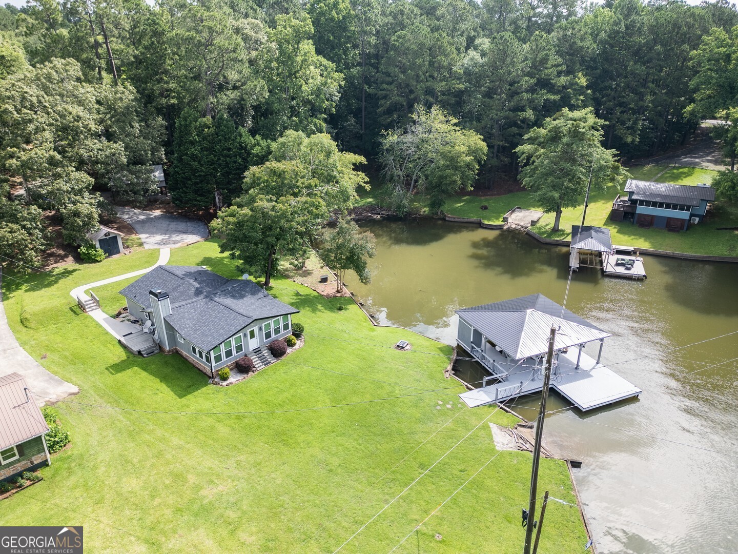 Comfortable move in ready lakeside retreat! This 3-bedroom & 2-bathroom home with approximately 272 feet of waterfront on 1.26 +/- acres and a new covered dock with boat lift & sunning deck features a new architectural roof & gutters, open floorplan, new front windows overlooking the lake, custom hardwood floors, custom stone fireplace, updated kitchen and primary bath, stainless steel appliances, all appliances are staying including the washer & dryer and oversized HVAC. Property also includes plenty of parking, a cement seawall, private boat ramp, carport, large workshop/shed, well cared for lawn and irrigation system from the lake to keep the grass nice & green year-round! Enjoy the beautiful sunsets from your peaceful & level lake property!