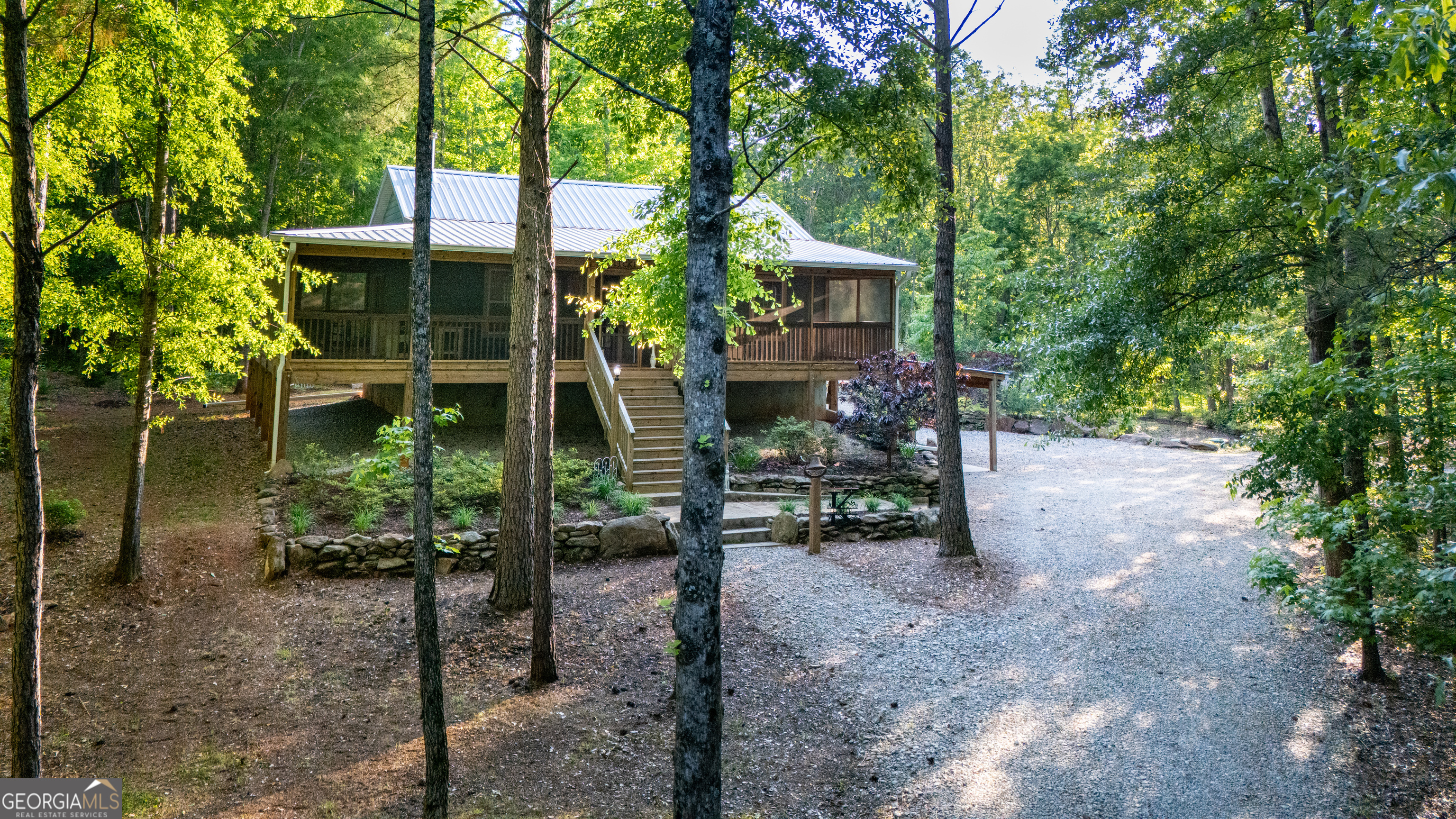 TWO HOMES * SECLUSION * HOMESTEAD * HUNTING RETREAT * FAMILY COMPOUND * PRIVATE OASIS...This property can be whatever you dream it to be! Arrive beneath a canopy of trees on this 12+ acres and the MAIN HOUSE (over 1900 sq ft) will immediately charm with a wide wrap-around screened porch, stacked-rock garden walls, and lush landscaping. Step inside and the craftsmanship is undeniable, warm pine walls, a soaring tongue-and-groove cathedral ceiling, and a stacked stone hearth framing a cozy wood-burning stove. Every detail tells a story, with walls, trim, cabinets, and even countertops milled from the very trees of this land. The open living area is tailor-made for gathering. in the kitchen, an island with a decorative copper farmhouse sink pairs beautifully with poplar cabinetry and cherry countertops (also milled on site), a breakfast bar, pantry and recessed lighting. The dining area opens through French doors to the screened porch for effortless indoor-outdoor meals. Just off the kitchen, a spacious bedroom with walk-in closet sits across the hall from the upstairs full bath, complete with a tub/shower combo, a large vanity, and a double-door linen closet. Head downstairs to a versatile first level: a second great room, a laundry room with built-ins and a sink, and a flex room perfect for an office, craft space, playroom or even a third bedroom. The primary suite features a walk-in closet with safe and a spa-style bath with an oversized vanity and an extra-large tiled walk-in shower. A door from the laundry room leads to the two-car carport and circular drive for easy comings and goings. Just to the left, the GUEST HOUSE (about 800 sq ft; not included in main square footage or bed/bath count) was built a little over a year ago with accessibility in mind with wide doors, a stepless tiled shower, and an open, airy plan. It mirrors the main home's character with pine and poplar walls, cathedral tongue-and-groove ceilings, solid wood sliding barn doors, a farmhouse-style kitchen with pantry and island, and a serene bedroom with walk-in closet and full bath. Both homes were designed for resilience and comfort: 15" storm-rated walls on the main house's lower level, outdoor showers, tie-down-reinforced walls and porches, LVP flooring, metal roofs, a GENERAC 24 kw whole-house generator, and even an emergency manual deep-well hand pump. Outside is a homesteader's and outdoorsman's dream. Multiple outbuildings include a 52x26 structure (approx. 20x26 enclosed) with power, workspace, RV/boat storage, and two 50-amp hookups; an 18x22 building with power (100-amp service with 30-amp washer/dryer option); plus, additional powered building, a chicken coop with enclosed yard, and more. Wander the orchard-apple, pear, persimmon. peach, banana, and black walnut-pick blueberries and blackberries, tend the garden, and explore ATV trails that ribbon across the acreage. With Rock Mills Rd frontage, there's flexibility to subdivide or add future family homes if desired. All this, just minutes from West Point Lake, Pyne Road Park, the Alabama state line, and Heard County. If you're seeking quality, privacy, and a true safe haven, one that can be a homestead, hunting retreat, multi-generational compound, or private oasis, this property is ready to welcome you home. You have to see this property to understand the value and appreciate all it has to offer!!
