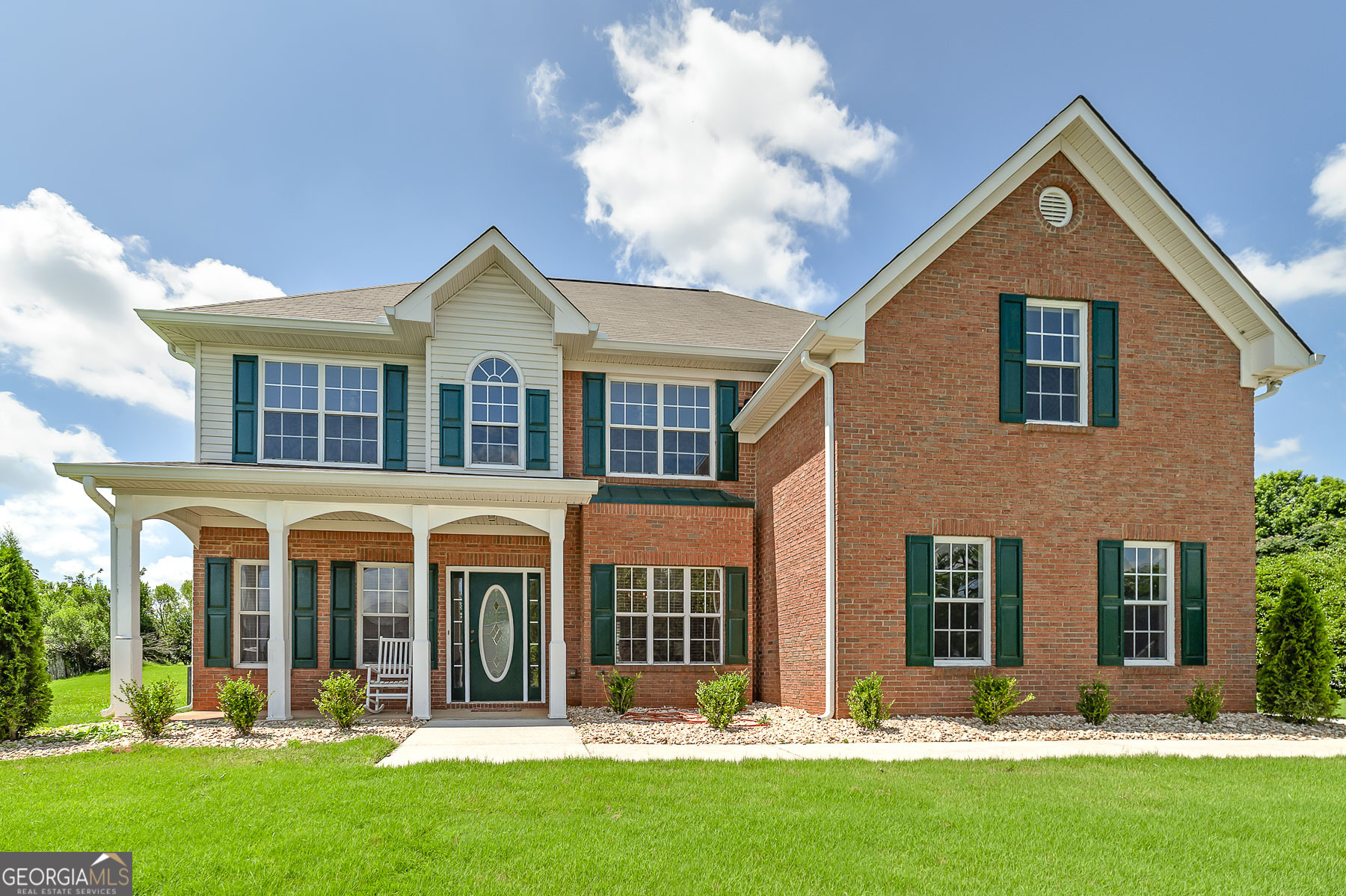 Room for everyone in this lovely traditional style brick front, low maintenance home. A covered rocking chair front porch welcomes you as you enter a grand two-story foyer with lots of natural light and beautiful hardwood floors. On one side of the foyer, you will find a spacious flex room - perfect for a home office or music room. The opposite side of the foyer is the formal dining room with plenty of wall space for a buffet and china cabinet. The kitchen is nicely appointed with lots of countertops and stained wood cabinets reaching to the ceiling, a cozy breakfast bar, with a large pantry in the breakfast area encased in a light filled bay window. A favorite feature is the bedroom and full bathroom on the main level - perfect for guest's privacy. A very convenient mudroom leads to the 2-car garage. The great room is open and airy with a brick surround gas starter fireplace. Upstairs you will find four more bedrooms! The primary bedroom is absolutely huge! It has a sitting room that could serve as a nursery, home office or a magnificent closet - with two additional large walk-in closets on each side. The ceramic tiled ensuite bathroom is just as spacious with a soaking tub, separate shower and two vanities. Three additional guest bedrooms are very nice sized, and the hall bathroom has a two-sink vanity and a tub/shower combo. Abundant number of closets for lots of storage throughout! The laundry room is located adjacent to the primary bedroom. Moss Pointe is a beautiful small subdivision with very low HOA fees and close to medical centers, great Union Grove schools, lots of shopping, and dining options!