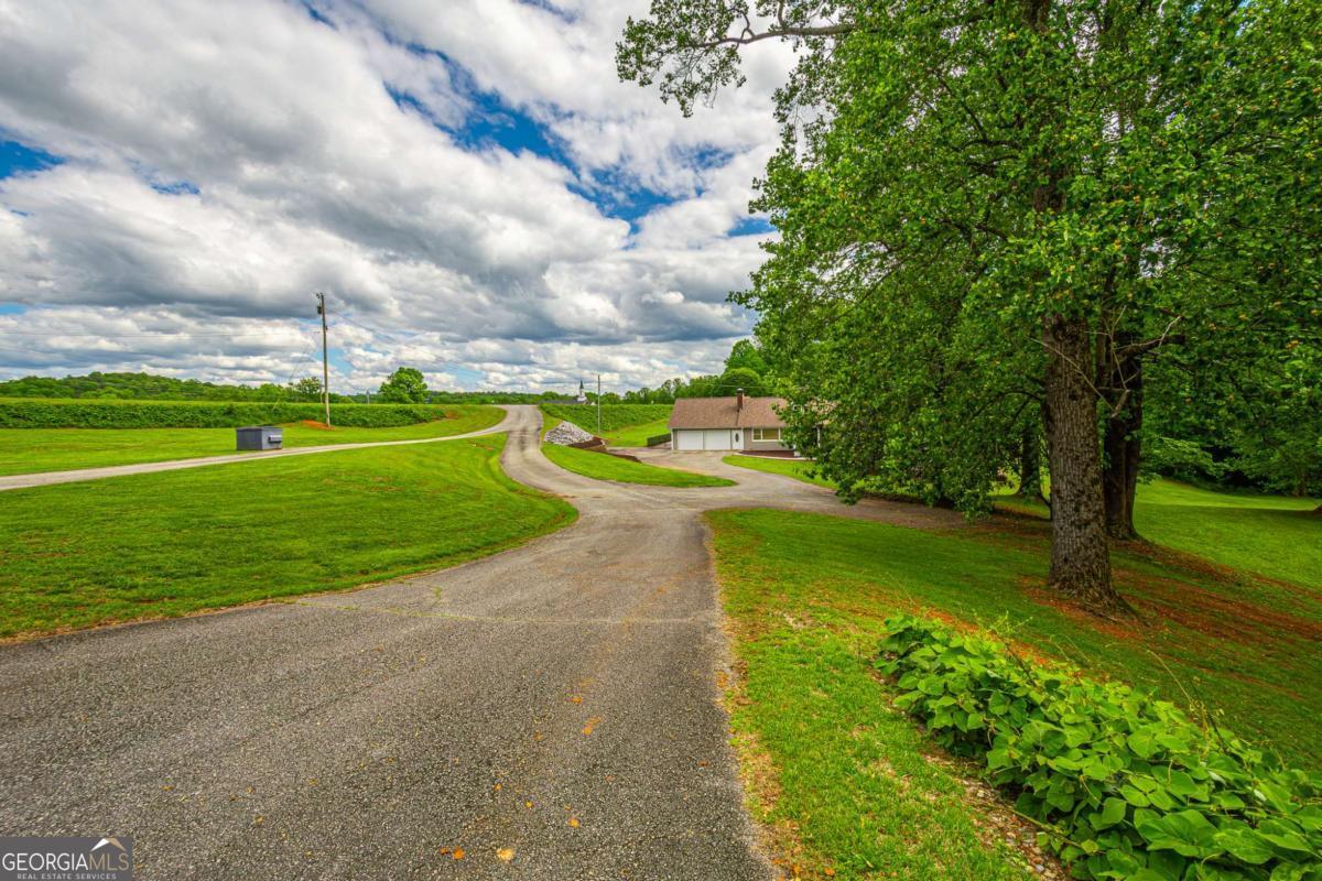 Imagine spending your days on beautifully manicured rolling green acreage with a well built home and a sprawling 5600 sq ft shop on one of the most beautiful roads and best locations in all of the county! Presented for the first time on the market in over 50 years, this is a rare opportunity for a well established estate sized tract mere minutes from Downtown Dahlonega, wineries, trout streams and all that the beautiful North Georgia adventure region has to offer. The beauty, versatility and convenience of this property cannot be overstated. The, approximately 2500+/- sq. ft. home with enormous unfinished daylight basement is a blank canvas waiting for your color choices, updates and finishes and the shop is a sprawling space ready for business or can be re-configured to suit your needs. All this plus an oversized "L" shaped salt-water pool and pool deck just in time for summer! Approximately 7+/- acres with multiple building sites, house, shop, pool and room to breathe.