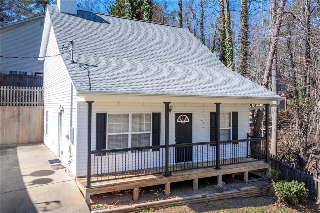 View of front of house with roof with shingles, a chimney, and covered porch