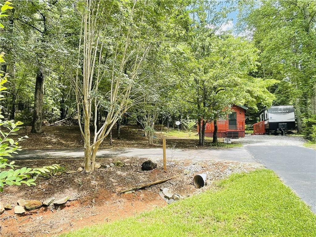 Escape to the beauty of the North Georgia Mountains in the sought-after Paradise Valley Campground, conveniently located near Cleveland, Helen, and Dahlonega. This unique and spacious 1 +/- ac corner lot with cabin features two full hookups and a camper making it perfect for hosting guests, setting up multiple RVs, or expanding your vacation space. Included in the sale is a lightly used and a 2021 Hideout Camper that has only been slept in a handful of times, offering immediate use and value. The cabin is currently under construction with potential for a loft-providing flexibility to customize your mountain retreat just the way you envision.
Surrounded by nature and outdoor adventure, this location puts you close to everything North Georgia has to offer. Explore local wineries, enjoy day trips to Unicoi and Vogel State Parks, or hike parts of the legendary Appalachian Trail. The area also offers whitewater rafting, kayaking, scenic drives, and charming mountain towns filled with restaurants, breweries, and artisan shops.
Paradise Valley Campground offers a well-maintained and welcoming community with amenities like a swimming pool, clubhouse/pavilion, and regularly scheduled activities for those who enjoy a sense of community and social interaction. A peaceful trout stream runs through the property, enhancing the serene environment. **Please note, this is a seasonal-use community and does not allow full-time living.**
This property is ideal for weekend getaways, part-time stays, or vacation rental potential. Making this the perfect opportunity to own a piece of the North Georgia mountain lifestyle.