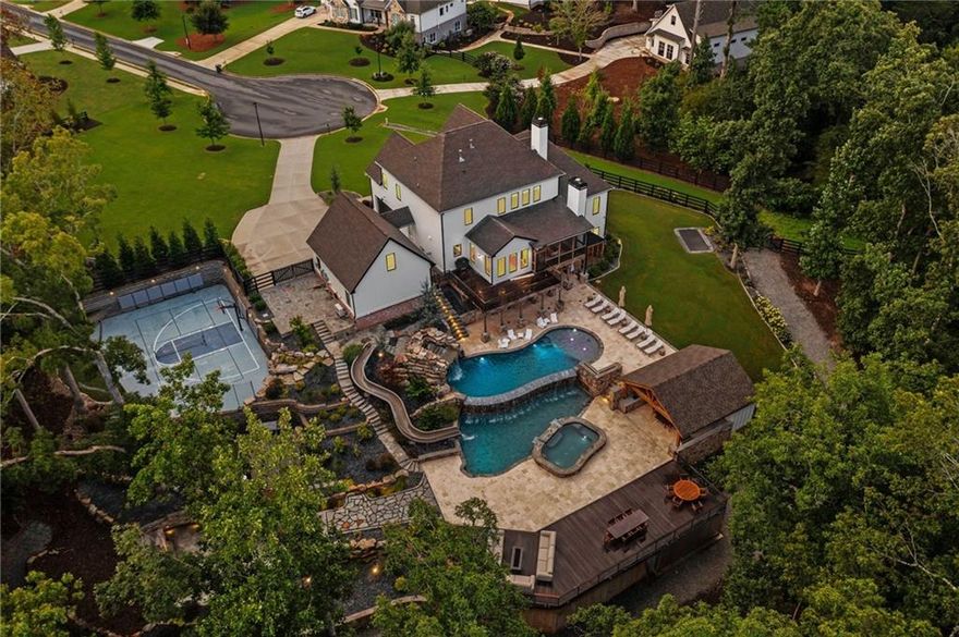 Once-in-a-Lifetime Luxury Estate with Resort-Style Backyard on 2.5 Acres - UNLIKE ANYTHING ELSE ON THE MARKET!
This extraordinary estate offers a rare opportunity to own a property that blends the ultimate in luxury living with resort-style amenities. Situated on 2.5+/- acres of lush landscaped grounds in a prime school district, this home is designed for entertaining, relaxation, and everyday comfort at the highest level. Inside, you’ll find gorgeous modern finishes with cedar beams throughout the main level, an open floor plan with a large family room that includes built-ins, cozy stone fireplace and sliding doors opening the indoors to the outdoors.  A massive gourmet kitchen featuring an oversized island with seating for up to 10, quartz countertops, double ovens, oversized refrigerator, and a vented range with hood. A vaulted keeping room/ breakfast area with shiplap and custom lighting adds to the charm of this spectacular home!  This luxury kitchen also offers a custom walk-in pantry with a grocery door makes everyday living effortless. The main-level primary suite is a private retreat with soaring ceilings and a spa-like bath including a soaking tub, oversized shower, and double vanity. Owner suite closet includes custom built-ins, island with drawers, makeup vanity/desk and FULL laundry with sink! Upstairs, four spacious secondary bedrooms each offer their own private en suite bath and walk-in closets. A second fantastic laundry upstairs with cabinets and sink. The finished terrace level includes a sixth bedroom, full bath, a state-of-the-art media room with seating for 10 and an incredible sound system, a fitness room, and a rec room. Terrace level also offers a third laundry making laundry a breeze on any floor! A whole-home speaker system carries throughout the interior and exterior, creating the perfect setting for entertainment.
The backyard is a true PARADISE with diving ledges, resort-style slides, waterfalls, grottoes, tanning ledges, and a massive hot tub, along with pickleball and basketball courts, a putting green, and an in-ground trampoline. Outdoor living continues with a full kitchen, outdoor bathroom, sauna, private outdoor shower and spectacular outdoor fireplace tucked in the trees for majestic evenings!  Covered and screened deck with fireplace is the perfect spot for morning coffee! Custom lighting enhances both the home and backyard, creating a stunning evening ambiance, while a full irrigation system keeps the grounds lush and a full house generator provides peace of mind. A rocking chair front porch adds classic Southern charm, while the attached two-car garage and detached two-car garage provide space for four vehicles in total. Above the detached garage, a private office / bonus space is ideal for a home office, studio, or man cave. The property also features a private hiking trail that leads directly to Canton Creek and waterfall.
This one-of-a-kind estate combines breathtaking design, unmatched amenities, and an outdoor resort experience unlike anything else on the market.