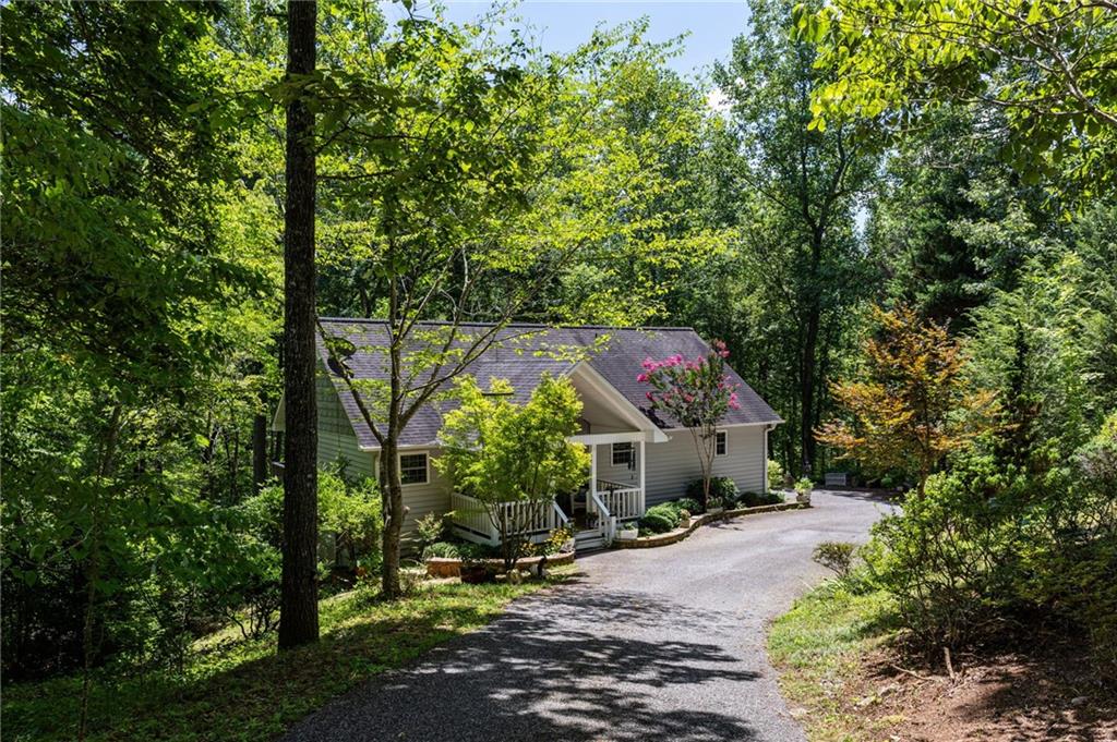 Charming creekside cottage in the heart of Hiawassee, tucked near the end of a quiet cul-de-sac with seasonal views of Bell Mountain and the relaxing sound of Bell Creek just beyond the backyard. From the moment you arrive, you’ll feel at ease surrounded by nature, an English garden blooming year-round, and the peaceful setting of the North Georgia mountains. Tube or wade right into the creek from your backyard, or enjoy the community picnic area along Bell Creek, perfect for gathering with friends and neighbors.
Inside, the home balances warmth and function with hickory wood and ceramic tile floors, double-pane windows, and an inviting gas fireplace in the living room. The updated kitchen includes granite countertops, custom cabinets, soft-close drawers, a movable island, and stainless steel appliances. A mud room sits conveniently by the entry. The main-level primary suite offers a spa-like bath with a soaking jet tub and a huge walk-in closet. Bathrooms are updated with granite counters, and the laundry room is located on the main level for convenience.
The finished terrace level adds flexibility with soaring 10+ foot ceilings, a massive stone fireplace, a full kitchen, washer/dryer hookups, and a private entrance—making it ideal for an in-law suite, guest quarters, or rental potential. New carpet has been added to the stairs, and the home provides abundant storage throughout.
Additional features include high-speed fiber internet for seamless work or streaming, and furnishings negotiable with sale. This one-owner home has been impeccably maintained since construction and is truly move-in ready.
Located just minutes from Lake Chatuge for boating and fishing, Jack Rabbit State Park for hiking and biking, and year-round concerts and festivals at the Georgia Mountain Fairgrounds. This property offers not only a beautiful home, but also a lifestyle surrounded by the best of North Georgia recreation, culture, and natural beauty.