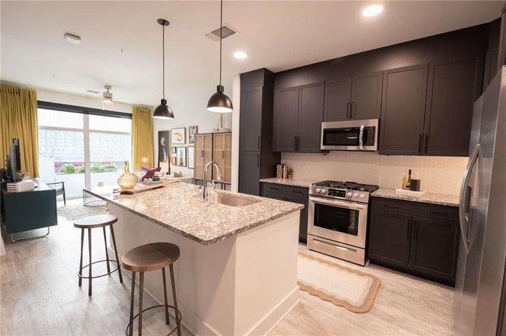 Kitchen featuring appliances with stainless steel finishes, a kitchen island with sink, a kitchen bar, sink, and light…