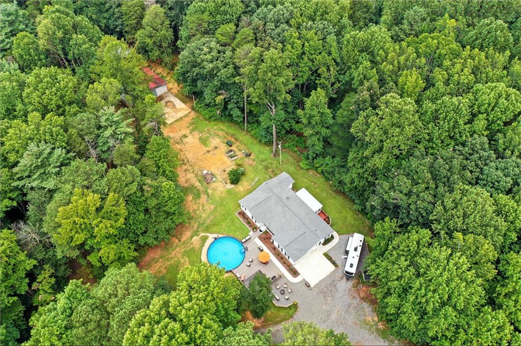 Country living with room to grow on acres! This well-maintained 3-bedroom, 2-bath ranch home is situated on 5.9 acres of peaceful land—perfect for those looking for space and privacy. This charming home offers potential in a beautiful rural setting. Inside, the home features a functional layout with a cozy living area, spacious kitchen, and comfortable bedrooms. The master bedroom is on the main level and includes an en-suite bath. Both of the secondary bedrooms are generously sized and have walk-in closets. The living room has a fireplace and a bay window. The country kitchen is well equipped and has a kitchen peninsula with seating for 4. The eat-in kitchen nook has room for all your guests. The enclosed back porch is perfect for morning coffee or for entertaining. There is a large pantry/ storage room off the kitchen perfect to keep all of your things. Step outside and enjoy summer days at the above-ground pool and relax and entertain on the large Trex deck —durable, low-maintenance, and built to last! Entertain your guests at the fire pit under the bright stars found only in the country away from the bright city lights. Whether you're hosting friends, enjoying a quiet morning coffee or end-of-day beverages, the outdoor space is sure to impress. Included on this property is a separate barndominium in process with a large parking pad/slab that has a newly installed septic system. This project was started by the seller and it offers a fantastic opportunity to finish this project your way. Cabinets, new kitchen appliances and a water heater will be included. Large concrete pad next to this structure is in place for a parking area or when you build the new garage. Whether you're dreaming of a guesthouse, workshop or studio, the groundwork is already in place. With almost 6 acres to roam, there's plenty of room for animals, gardening, or simply enjoying nature. No HOA. Bring your vision and enjoy all the benefits of country life just a short drive from Ellijay. So many upgrades to list here. This property has a new Generac back up power system. There are two wells on the property and one was just completed in 2024. Crawl space under the 3 bedroom home has a recently installed vaper barrier and is humidity controlled. Don’t miss the chance to make this property your own—schedule your private tour today!