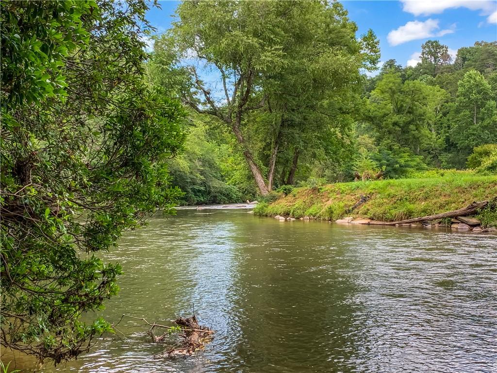 Welcome to Lot 17 Misty Mountain Trail - an exceptional opportunity to build your dream mountain retreat on the banks of the Cartecay River! Located within the prestigious, gated community of The Bluffs of Cartecay, this 1.5-acre lot offers a rare combination of natural beauty, prime location, and modern convenience. Boasting 38 feet of direct frontage on the rushing Cartecay River, this property allows you to enjoy the soothing sounds of the water year-round and the potential for riverside amenities such as a fire pit, seating area, or private access for fishing, kayaking, or simply relaxing. The lot features gentle, buildable terrain, making it an ideal canvas for your future full-time residence, vacation getaway, or short-term rental investment. The lush hardwoods and serene wooded views provide an unmatched sense of peace and privacy, while still being less than 5 minutes from historic downtown Ellijay. From charming boutiques and cozy cafes to farm-to-table restaurants, local wineries, and seasonal festivals-everything you need is just around the corner. Community perks include underground utilities, paved roads, and secure gated access, ensuring both ease of development and long-term value. And unlike many mountain properties, strong cell service is available, so you can stay connected without compromising your secluded lifestyle. Whether you're envisioning a luxurious cabin perched above the river or a modern rustic getaway nestled among the trees, Lot 17 provides the perfect backdrop for your vision. Properties with this combination of river access, location, and infrastructure are becoming increasingly rare in North Georgia-don't miss your chance to own a piece of this stunning landscape. Contact us today to schedule a private tour and explore the potential of this remarkable property. Map GPS to 327 Aspen Avenue, Ellijay, GA 30540. Lot is right across from this home. From Walmart in Ellijay, turn L onto Highland Parkway. In 1.1 mi, turn L onto Yukon Rd. In 1.1 mi, turn R onto Old Bennett Road. In 0.7 mi, turn R onto Aspen Ave. In 0.3 mi, the destination is on your Right.