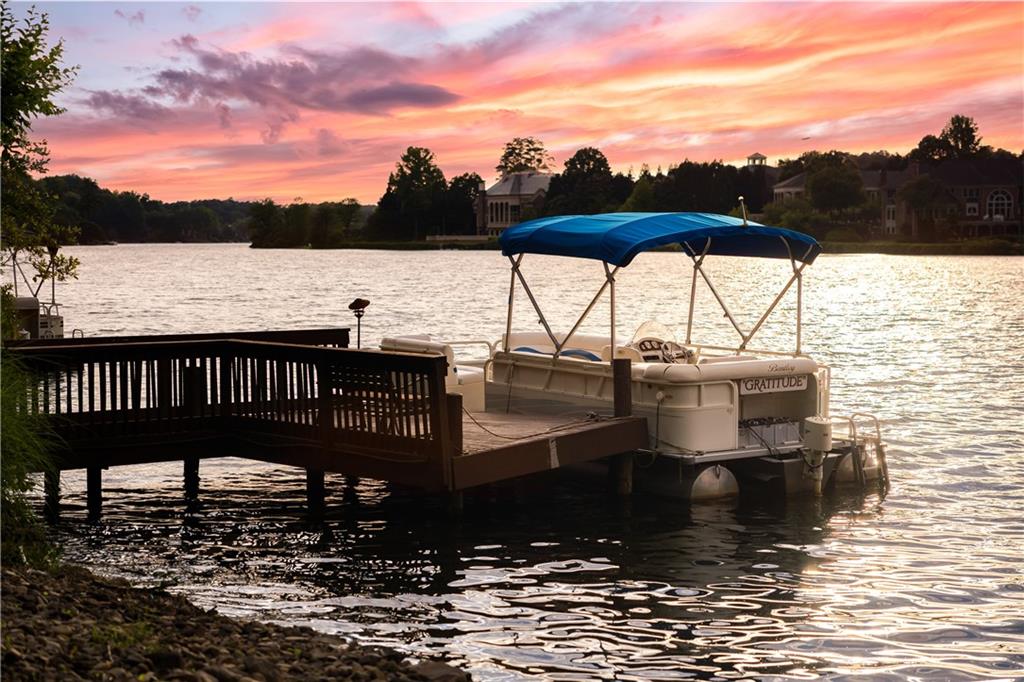 This is the lake home you have always been dreaming of-THE BEST lot on Lake Windward AND so close to Alpharetta & Avalon! Breathtaking views of the lake with approximately 114’ of waterfront property, as well as views of Golf Club of Georgia's 14th Green. The home has been site to capture sunsets that are indescribable! The main level includes a sophisticated Living Room with Coffered Ceilings, Formal Dining Room for 10-12 with views of the lake & golf course. Open Concept Kitchen flows into 2 story Great Rm, all glass Solarium & Breakfast area, ALL with views of the lake and access to the very large multi-level wrap around deck. Your dream Primary Suite is also on the main level, with sitting area, fireplace and lake views & cool breezes to wake up to. The primary suite & bathroom is ADA compliant with huge zero entry dual head shower, and offers generous space for the owner, along with a lift to the lower level. Upstairs is a generous 2nd potential Primary Ensuite Bedroom with Sitting Rm with Bookcases & desk. This suite is a true retreat with Window Bench overlooking the lake. Additional 2
very spacious Bedrooms with Jack & Jill Bathroom.
The lower level offers fun for everyone. There is an Office/Bedroom Rm with a Murphy Bed, Media/Game Rm room that spans much of the lower level with spectacular views and access to a covered deck, Bedroom & Bath and an additional space that could be a wine room or gym. The outdoor living space is an entertainer's dream! This multi-level deck offers shade and views unparalleled to anything on Lake Windward! Mature landscaping and paths lead to the dock. Pontoon boat is included in the sale of the property. Professional Pictures coming soon!
The highly desirable Windward community is close to GA-400, The Greenway Trail, Avalon, and the best of Alpharetta and Milton within 5+ minutes. With several business parks within Windward, many residents work close to home and golf, fish or boat in the afternoons, either from their dock or the Yacht Club. The Windward Lake Club offers 4 pools, tennis courts, pickleball and the marina. There are two playgrounds, sports park and a dog run. The Golf Club of Georgia offers two 18-hole courses that wind through the Windward community. Members of the Lake Windward Club can enjoy a tennis center with 16 courts, an Olympic-sized swimming pool and kiddie pool. Additional amenities include soccer, softball and football fields within the Windward Sports Park.
Top-rated schools, access to the greenway, moments to 400, Windward Lake Club, and a staycation home...what more can you ask for?