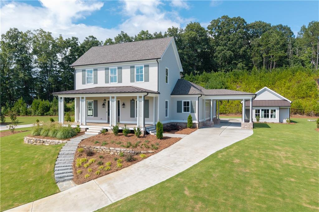 Situated on over an acre of beautifully landscaped grounds in the Estate section of Crossroads, this entertainer focused custom-built home perfectly balances elegance with modern comfort. Featuring a port cochere and detached three-car garage, it combines style, convenience, and functionality. Designed for those who love to host, this home’s open flow and thoughtful details make every gathering effortless. Step into the foyer adorned with stained pecky cypress trim and immediately notice the generous office with detailed wall finishes. The oversized family room, anchored by pecky cypress accents and a cast concrete fireplace surround, opens through French doors to an expansive brick patio, seamlessly connecting indoor living to a backyard perfect for a dream pool or outdoor entertainment space. The chef’s kitchen is ideal for entertaining, featuring an oversized island with a microwave drawer, dedicated storage for pots and pans, a farmhouse sink, and two dishwashers. The professional-grade 48" Thermador gas range with six high-output burners, griddle, and double ovens serves as the centerpiece, framed by blue and light gray cabinetry reaching 10’ ceilings and a custom Subzero refrigerator enclosure. The main-level primary suite provides direct access to the covered porch, a custom-built closet, and a spa-like bath. A guest bedroom on the main floor ensures comfort and privacy for visitors. Upstairs, a spacious bonus room or spacious 5th bedroom, two bedrooms with en-suite baths, and an open loft offer flexible space for family, entertaining, or a home office. Blending sophisticated design with seamless functionality, this home delivers an unmatched Milton lifestyle and a floor plan made for hosting with ease and elegance.