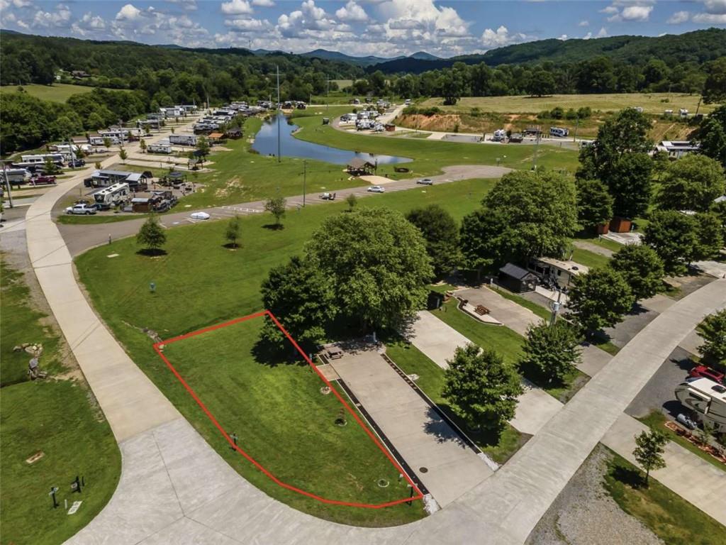 With featured community amenities such as: a dog park, several covered outdoor pavilions/picnic areas, an outdoor pool, restrooms and showers, a clubhouse, wood-fired pizza ovens, a playground, golf-cart rentals, 4 community fire pits, a gaga ball pit, outdoor basketball court, disc golf, picnic area, a stocked community lake, a 5br vacation home, tiny homes and RV's for nightly rentals, wi-fi and cable TV, laundry facilities and vending area--to name a few, in Waterside at Blue Ridge, boredom is a thing of the past! Alternatively, if you're looking for a peaceful, relaxing getaway, this community also masterfully delivers with well-kept grounds, posted community guidelines and speed limits, park rangers, gated entry, and homeowner's association. Now, let's talk about this amazing lot! Situated on a corner is lot #63--one of the only remaining privately owned held grassed lots in the community, leaving the end-buyer more autonomy as to whether to pave, place gravel, or keep as-is to enjoy the beautiful, soft and cushy, cool grass under your feet as you step out of your RV or camper. Perhaps your dream is to build a tiny home that you can stay in, either full-time or part-time, while bringing in short-term rental income when you're away, and if you choose not to build at all, with sewer, water, and power hook-ups, you can always rent out the lot! With Lake Blue Ridge located just 2.5 miles away, this community is conveniently located just far enough outside Metro Atlanta to where you feel like you're really "getting away" or going on a true camping trip, but close enough to "civilization" and downtown Blue Ridge where you can still go for a grocery run at Ingles, Aldi, or Food Lion; go to dinner at the highly rated Mike's Trackside BBQ, Boatdock Bar & Grill, or Southern Charm Restaurant; or go shopping at Wal-Mart, Roses, TJMaxx, or the Blue Ridge Mountain Mall. Schedule a showing today, reach out with any questions, and see yourself at Waterside at Blue Ridge--a lovely tiny home and RV park community with plenty to do, making it a perfect vacation and gathering spot for the entire family!