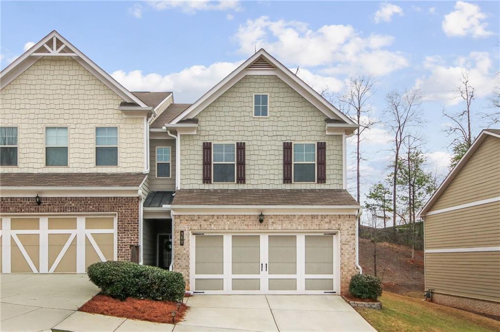 Craftsman-style home featuring driveway, a garage, and brick siding
