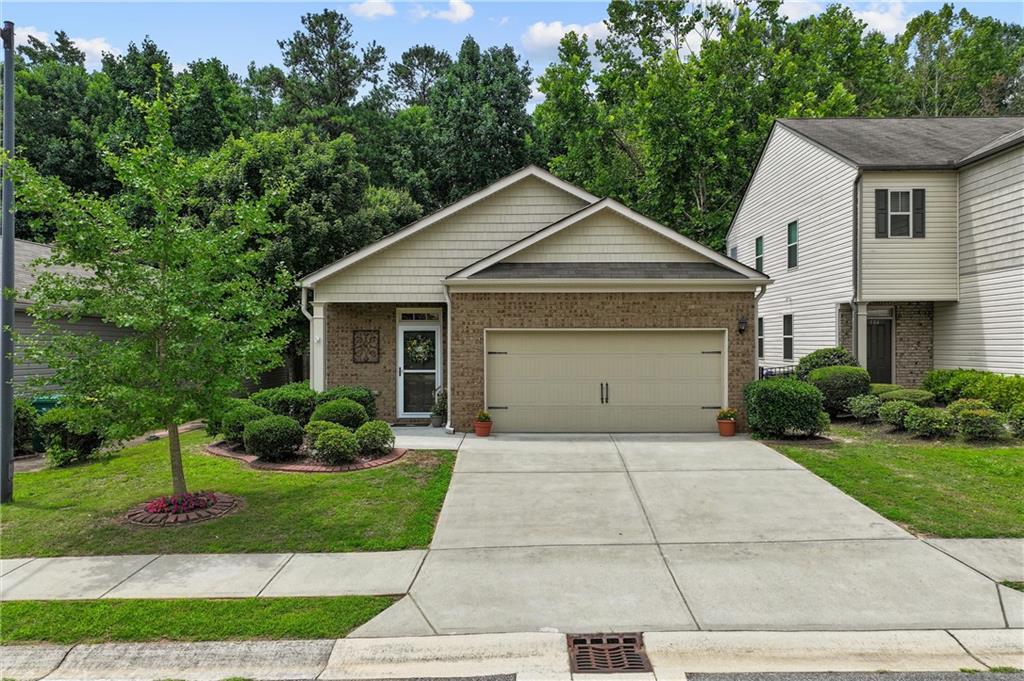 Brick and siding exterior with an attached garage, concrete driveway, and established front landscaping