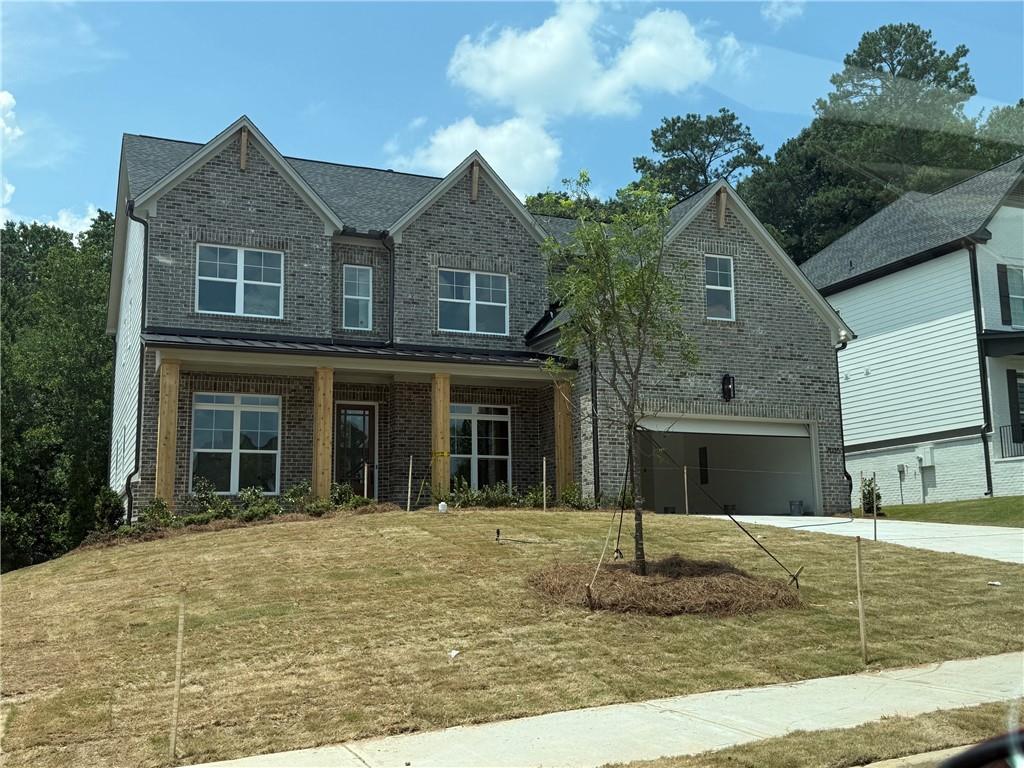 Two-story residence featuring a gray brick facade with white siding accents, multiple gables, and a dark shingle roof