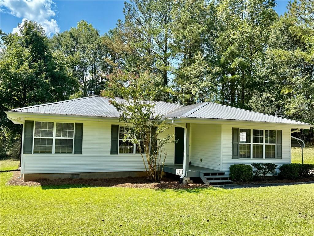 Escape to the countryside with this charming home set on 1 acre of land. Featuring 3 bedrooms and 2 bathrooms, it offers a cozy and functional living space. The exterior is low-maintenance vinyl siding and a durable metal roof, ensuring easy upkeep. Enjoy spacious front and back yards, perfect for outdoor activities, along with covered porches at both the front and rear for relaxing outdoor gatherings. Ideal for those seeking peace and privacy in a picturesque setting.