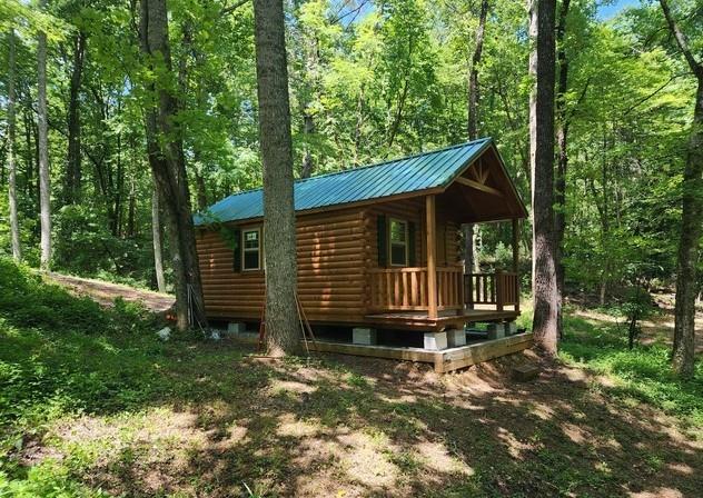 Discover 7.7 acres of pure privacy in the heart of Ellijay! This unique property is unrestricted with no HOA, offering complete freedom to use it as you wish. A creek flows through the property with several flat, usable areas along the water, creating multiple scenic spots to relax or build. With 4-5 potential building sites and road frontage all the way around, the options are endless for building your dream home, family retreat, or multiple cabins.
The property already includes a 12x24 hunting cabin built in 2024, featuring double pane windows, AC (window unit), solar power with a generator backup, and fresh spring water that is drinkable. Inside you'll find a bedroom area, sink ready for water hookup, mini fridge, electric cooktop, and storage space, making it a cozy camping home while you build. A firepit is in place for gatherings under the stars. The land has a recent survey, perk test, and R1 zoning, making it ready for your next step. With excellent cell service, power nearby, and unrestricted use, this property is perfect for those seeking a weekend getaway, hunting retreat, log cabin build, or full-time residence in a quiet, natural setting. Map GPS to 120 Oak Hill Drive, Ellijay GA 30540. From here, when you see this home on your R, take a left directly across the road onto the old road bed. Follow road for about 1/4 a mile and see the property on the right. Sign in place. From Walmart Ellijay, head out of the parking lot and take Highland Xing to merge onto GA-SR 5 / SR 515 South. Follow SR 515 for about 1.6 miles, then turn right onto GA-SR 382. Continue along SR 382, and when you reach the roundabout, take the second exit to stay on SR 382. In 5.3 mi, turn R onto Oak Hill Rid. In 1.7 mi, turn L onto Oak Hill Drive. When you see 120 Oak Hill Drive, Ellijay GA 30540 on your R, take a left directly across the road on the old road bed. See property in about 1/4 mile on the right. Signs in place. Property lines are marked with ribbons all the way around, but Use landglide for property lines accuracy.