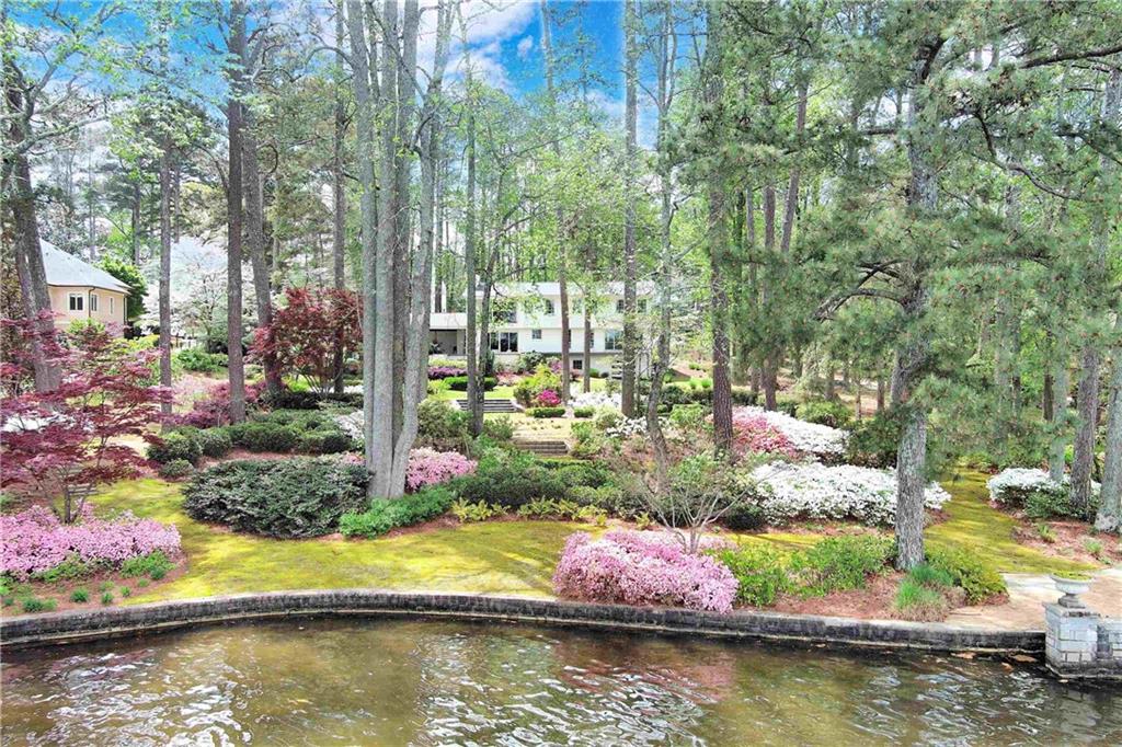 This house is a treasure. An exquisite two-acre, deep-water, terraced lakefront lot on private Lake Spivey. Over 214 feet of pristine lakefront, perfect for all activities like fishing, skiing, sailing, and rowing. The highlight of the lot is the magnificent stone seawall with a spacious brick patio projecting into the lake, complemented by a charming, Greek Revival-inspired, award-winning boat dock. The shoreline infrastructure provides an ideal setting for large gatherings of family and friends, offering incomparable views of the lake and the spectacular fireworks display on the 4th of July. The house has a northeast exposure on the lakeside, which allows for stunning sunrises over coffee and moonrises over cocktails from either the second-story deck off the primary bedroom or the first-floor deck and terrace. Both locations are perfect for taking in focused views of the lake over a garden where something is in bloom every season. The seamless transition from indoors to outdoors makes the house, shoreline patio, and dock ideal for every gathering. The architecture is traditional, with a welcoming porch leading into 3200 square feet of light-filled charm, including five bedrooms and four bathrooms. Beautiful hardwoods on the first and second floors. One guest bedroom and the primary bedroom both have en-suites. The primary bedroom boasts a cozy sitting area and a contemporary fireplace that can be enjoyed from either the bed or the sitting area. The open floor plan of the kitchen flows into a spacious and warm family room enhanced with rare wormy chestnut paneling, accentuated by an oversized fireplace. Both the family room and dining room area overlook the lake with a wide wall of windows showcasing the gently sloping terraced garden. The full bath on the first level accommodates swimmers and boaters and their gear. Downstairs offers an additional 1300 square feet of buildable space. Experience all the peace and tranquility of lake living, just 5 minutes from I-75, 20 minutes from Atlanta International Airport, 25 minutes from downtown Atlanta, and 30 minutes from Atlanta's premier shopping districts. Costco and Starbucks are a mere 7 minutes away, along with a variety of restaurants and other conveniences. Altogether, this property has an overwhelming sense of place - it's pure magic!