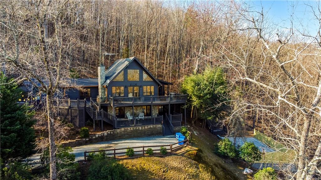YOUR DREAM MOUNTAIN LAKE RETREAT AWAITS! Just added a new PICKLE BALL COURT on property! Breathtaking lake and mountain views surround this stunning rustic cabin, inspired by traditional Italian architecture and designed for year-round beauty and relaxation. Whether you're sipping coffee on the expansive upper deck or unwinding on the cozy lower deck, every angle offers a spectacular backdrop of nature's finest. Step inside to a grand open living space, where a charming wood-burning fireplace sets the perfect ambiance. The chef's kitchen is fully updated with stainless steel appliances, sleek granite countertops, a wine fridge, and a spacious walk-in pantry-ideal for entertaining. The main-level master suite is a private oasis, offering direct access to the deck with breathtaking lake and mountain views. Indulge in the spa-like master bath featuring a soaking tub, beautifully tiled shower, double vanities, and luxurious HEATED FLOORS. Upstairs, a private loft bedroom and en-suite bath create a serene escape, while the finished basement boasts two additional bedrooms, a full bath, and plenty of storage. Every detail has been thoughtfully upgraded, including a brand-new hot tub, new HVAC system, upgraded well equipment and plumbing, plus a freshly painted home and deck. Located just 10 minutes from downtown Blue Ridge, this cabin is SOLD FULLY FURNISHED AND TURNKEY, making it perfect as a luxury getaway or an income-producing rental with a strong rental history. This is more than a cabin-it's an experience. Don't miss your chance to own this mountain-lake paradise!