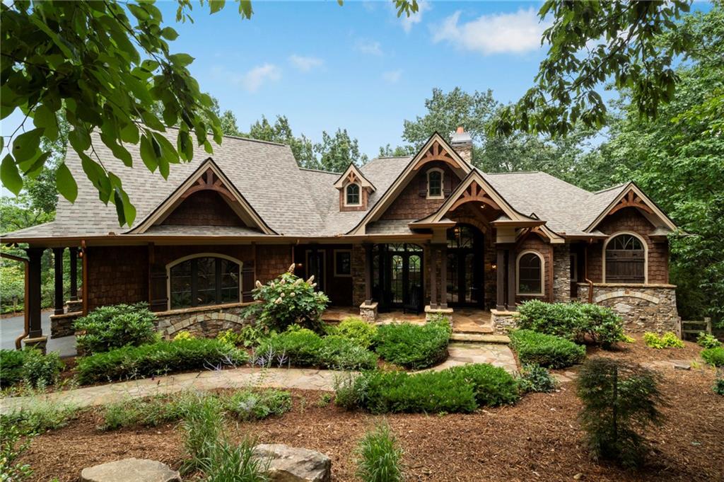 Stunning Custom Home built in the desirable Wildcat neighborhood of Big Canoe. With recent vista pruning it has breathtaking Mountain Views! Set on a level lot along Bluestern Drive, this residence boasts many improvements, beautifully updated landscaping, and convenient access to the North Gate and scenic Wildcat trails.
As you approach the home, you’ll be drawn in by its captivating mountain-style architecture and elegant exterior finishes. A serene stone walkway, bordered by lush perennial gardens, leads you to a welcoming stone front porch. Mornings you can enjoy the sunrise as you sip your coffee. This tranquil setting sets the tone for the peaceful living experience that awaits inside.
Upon entering through the grand entry, you’ll be greeted by rich wood floors, soaring vaulted ceilings, and hand-crafted chandeliers that showcase the home’s timeless character. The Great Room impresses with its arched windows, magnificent wood beams, and a stunning floor-to-ceiling wood-burning stone fireplace with gas starter, creating an inviting atmosphere for gatherings. The gourmet Kitchen is a chef’s dream, equipped with custom cabinetry, paneled appliances, a spacious island, a Wolf range, and a Sub-Zero refrigerator. Enjoy casual meals in the sunlit Breakfast Room, highlighted by a uniquely shaped tray ceiling. The adjacent Keeping Room offers another cozy retreat, featuring a fireplace, coffered ceiling, and picturesque views of Potts Mountain. An artist’s Studio off the Kitchen provides built-ins and inspiring mountain vistas, ideal for creative pursuits. The main-level outdoor living areas include a covered porch with a fireplace and a curved open deck, perfect for entertaining or simply soaking in the views and sunset hour. The luxurious Primary Suite is a true sanctuary, featuring a wood-accented tray ceiling, private deck access, and expansive windows. The spa-like bath includes an arched ceiling, an oversized shower, dual vanities, and his-and-hers walk-in closets with custom shelving.
The Upper Level offers a versatile retreat, complete with two bedrooms, a full bath, and a shared living area—perfect for guests, teens, or in-laws seeking their own space.
On the Terrace Level, the open layout and 10-foot ceilings create an inviting atmosphere for entertaining. Enjoy a stylish slate-accented Family Room with a fireplace, a large Game Room, and a wet bar featuring a copper sink and paneled appliances. This level includes two bedrooms and a beautifully appointed Jack-and-Jill slate bath, along with additional flex space that can serve as a theater room, gym, or extra sleeping area. A walk-out workshop and expansive stone patio complete this lower level.
Recent Updates Include:
New architectural roof,
Three new HVAC systems,
New hot tub and sauna,
Epoxy-coated garage floor,
Updated landscaping,
New ceiling fans.
A FULL LIST OF UPGRADES ARE IN THE PHOTOS and documents online.
This home is a true masterpiece of craftsmanship, comfort, and design. Seize the rare opportunity to own this exquisite custom-built home. Schedule your private showing today.
***A mandatory $4,500.00 capital contribution fee paid by the purchaser to the Big Canoe Property Owners’ Association will be due at closing. Pursuant to Article II, Section 1, Paragraph bb of the Class “A” Covenants for the Big Canoe community, all property transfers are subject to the Big Canoe developer’s right of first refusal.