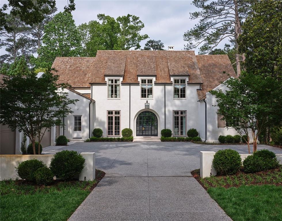 An exquisite 10,500-square-foot estate serves as the 2023 Southeastern Designer Showhouse. The custom-built residence on Normandy Drive is one of the latest projects by builder and developer Benecki, architect William T. Baker& Associates, landscape architect Land Plus and interior specification designers Source. 

The transitional home presents an airy, sun-drenched setting and showcases Baker’s mastery of classical architecture. An abundance of 12-foot ceilings, coved ceilings, and 10-foot doors and windows allow light to penetrate the residence. The architectural elements lean organic with rounder, soft curves and minimal ornamentation and millwork. A dramatic arched steel front door ushers in the homeowners and guests, where once inside, the floor plan generously offers views from the entry hall through the salon to the outdoor terrace and backyard. 

The residence’s overall design aesthetic is Streamline Moderne with Art Deco and Art Nouveau influences, while wabi-sabi design characteristics embrace the beauty of imperfection. Gold, burgundy and deep purple hues create a cohesive color palette. Venetian plaster, French oak hardwood floors, Calacatta Viola marble, brass fixtures and finishes, and Sub-Zero and Wolf appliances are among the features that amplify the interiors.

Situated on an acre in Buckhead, the new residence backs up to endless mature trees that create the feel of a countryside in the city. Timeless exterior choices, such as hard-coat stucco, and charming architectural elements, such as a cedar shake roof that flares at the dormers, are sensitive to the scale of surrounding homes in the established neighborhood. The salon and kitchen, with its barrel-vaulted ceiling, open to a terrace with an outdoor kitchen that leads to the lower lawn and pool.

The five-bedroom home, which has five full and three half baths, is designed for flexible living throughout the years. Primary bedrooms are placed on the main and second floors, and two laundry rooms offer ease of living. The main-level bathroom’s stunning touches include a barrel-vaulted ceiling, a sweeping shower with an elaborate mosaic, and marble countertops and floors. Spaces such as expansive dual closets in the primary bedroom on the main level, a pantry and caterer’s kitchen speak to modern homeowners’ demand for ample storage in style.

The floor plan, with a main-level study and an oversize TV/sitting room on the second level, recognizes the needs of families who entertain and work at home. The basement is outfitted for entertaining, exercise and relaxation with a lounge, home theater, game room, wine cellar, and gym with a sauna and massage room.