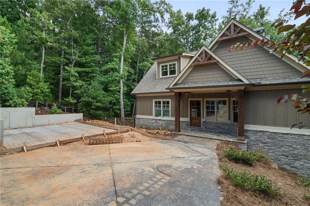 This 5 BR - 3 1/2 Bath design home is new construction and shows like a model with a brand new attached 2 car garage addition is in process, located in the very desirable cobblestone paved neighborhood 'Choctaw Village' near the Clubhouse in Big Canoe. Stunning Cedar beams in the family room. Hardwood flooring, upgraded lighting and custom features throughout. Enjoy the gorgeous two-story stone fireplace with ever changing, seasonal wooded views from the wall of windows. Custom Wellborn cabinetry in the kitchen with quartz counter tops, island with additional seating, stainless steel hood, 5 burner gas range/oven with air fryer feature. Open concept floor plan with access to the screened in porch with outdoor stone fireplace. Powder room features one-of-a-kind live edge vanity with vessel sink. Master on main features French door access to your outdoor living areas. His and hers walk in closets, modern soaking tub, custom Wellborn vanity and custom tile shower, quartz countertops. Two additional bedrooms and Jack and Jill bathroom on second level. Fully finished terrace level featuring custom wet bar with stack stone wall, butcher block countertop and custom floating shelving. Stacked stone wine cellar ready for your unique customization. Two additional bedrooms with full bath. Terrace level features high end LVP flooring, 8 ft interior doors, wall of windows and access to outdoor covered decks and patio. Garage/2 addition is attached via breezeway and well underway with a completion date of October 30th, 90 days or less. This is the only home currently for sale in all of Choctaw Village and close to all of the amenities, including walking trails out of your backdoor and within walking distance to the newly renovated and expanded Clubhouse and recently modified Golf Course, Choctaw and Creek both. This new home will come with a 1 Year Builder Warranty and is situated on a private cul-de-sac and located just minutes from the main gate entrance for ease of access in and out the community for good measure. Come see for yourself!