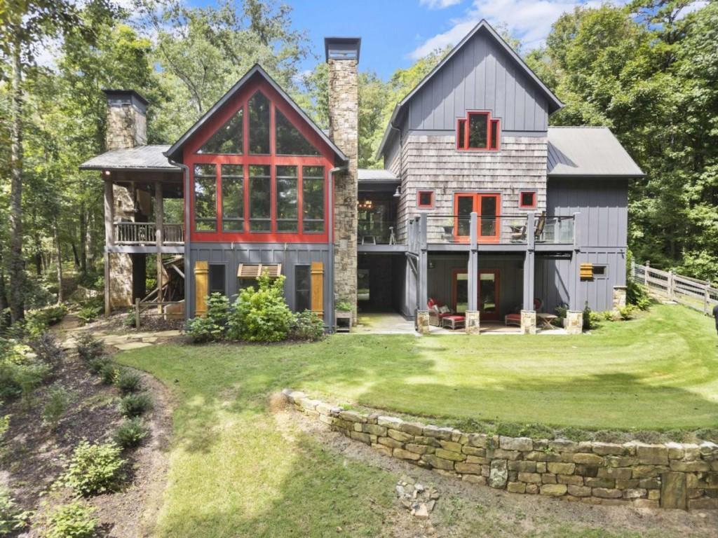 Escape to the heart of North Georgia wine country in this stunning 4 bedroom, 4.5 bathroom creekside luxury chalet, perfectly nestled in the mountains and less than five minutes from local wineries, apple orchards, and charming small-town attractions. Designed for both comfort and sophistication, this home combines rustic elegance with high-end finishes throughout. The main level welcomes you with soaring ceilings, walls of glass, and abundant natural light that frames beautiful views of Turkey Creek flowing just outside. Multiple stone fireplaces add warmth and ambiance, while an open floor plan seamlessly connects the great room, dining area, and chef's kitchen-ideal for entertaining or cozy evenings at home. This retreat offers space for everyone, with four spacious bedrooms each featuring a dedicated bath. The expansive primary suite is a private sanctuary, complete with a spa-like bathroom featuring an oversized tile shower, soaking tub, double vanities, and a walk-in closet. A bonus room offers flexible use as a home office, library, or playroom. For those who love to entertain, the lower level boasts a movie theatre and generous living space perfect for gatherings. Step outside to enjoy beautifully landscaped grounds, a creekside firepit, and multiple decks where you can relax and take in the fresh mountain air. Complete with a barn/workshop, a fenced area for your furry friends, and complete privacy, this would be a perfect full-time residence, private getaway, or income-producing investment. This North Georgia treasure is ready to welcome you home!