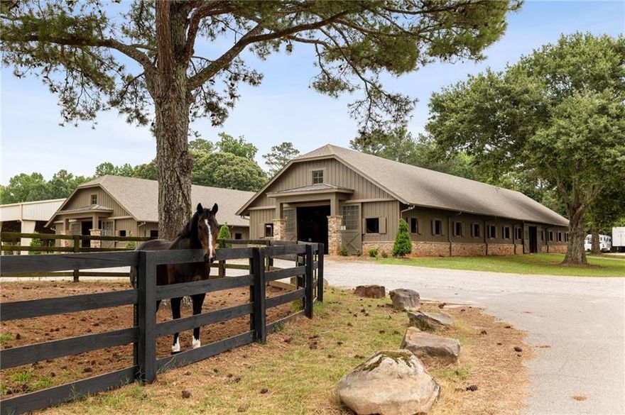 Seventh Hand Farm located in the heart of Milton offers the ultimate equestrian experience on 15 manicured acres.  This income producing property is located north of Atlanta convenient to Wills Park Equestrian Center, Alpharetta City Center and excellent schools.
The complex features a 20,000 sq foot barn featuring 38 stalls, 8 wash racks, a renovated patron's lounge, office, 2 temperature controlled tack rooms, large conference room, multiple bathrooms, laundry facility and 2 bedroom apartment with private upstairs balcony. The barn leads into a 160x300 covered and lighted arena compared in size to an Olympic equestrian arena with new GGR footing, a 140x280 outdoor arena with mirrored side, a 3-bay utility barn (for hay and farm equipment), additional 6 stall barn, additional turnout paddocks and 7 fenced pastures with double fencing and a bridle trail around the perimeter of the property. The main barn's stone arches and flooring and custom wood work makes this barn a world class facility.